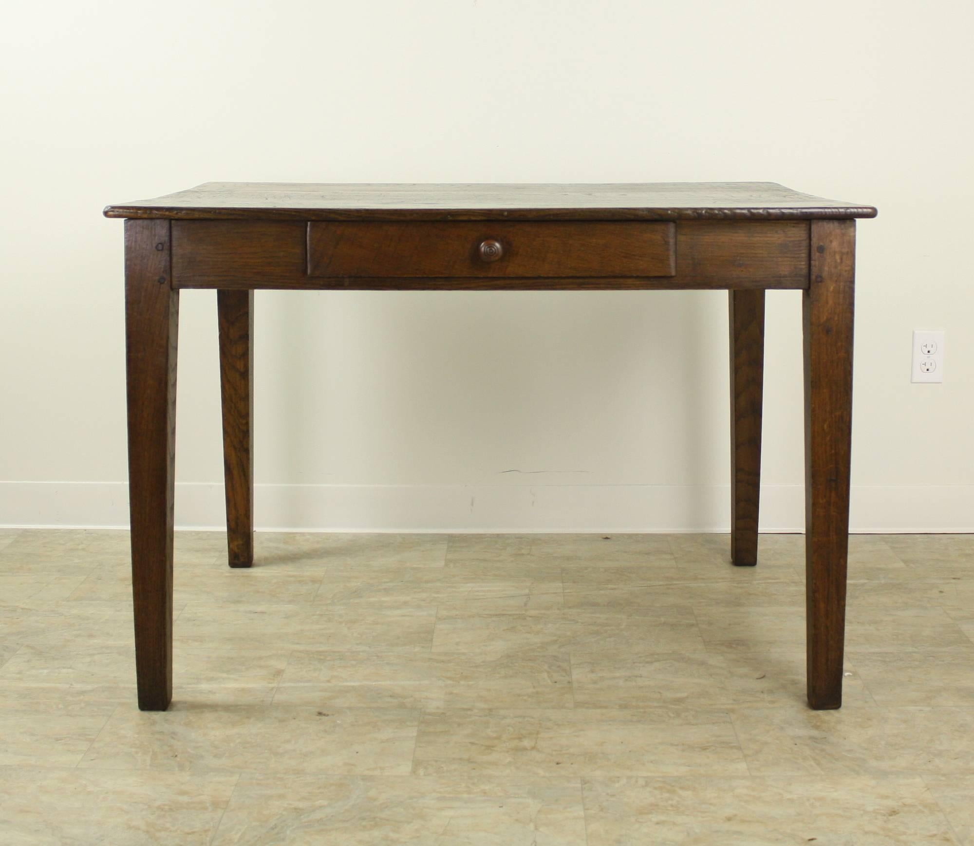 A handsome dark chestnut writing table with generous proportions on sturdy tapered legs. The wood has nice color and patina, and the extra depth of the piece makes it an elegant and functional work surface. One single drawer. At 25