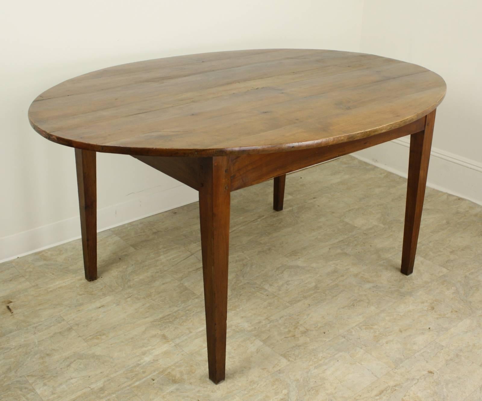 A simple and elegant oval dining table in mellow cherry with warm patina. The top is pretty and in good condition, nicely pegged at the legs. Apron height of 24.5