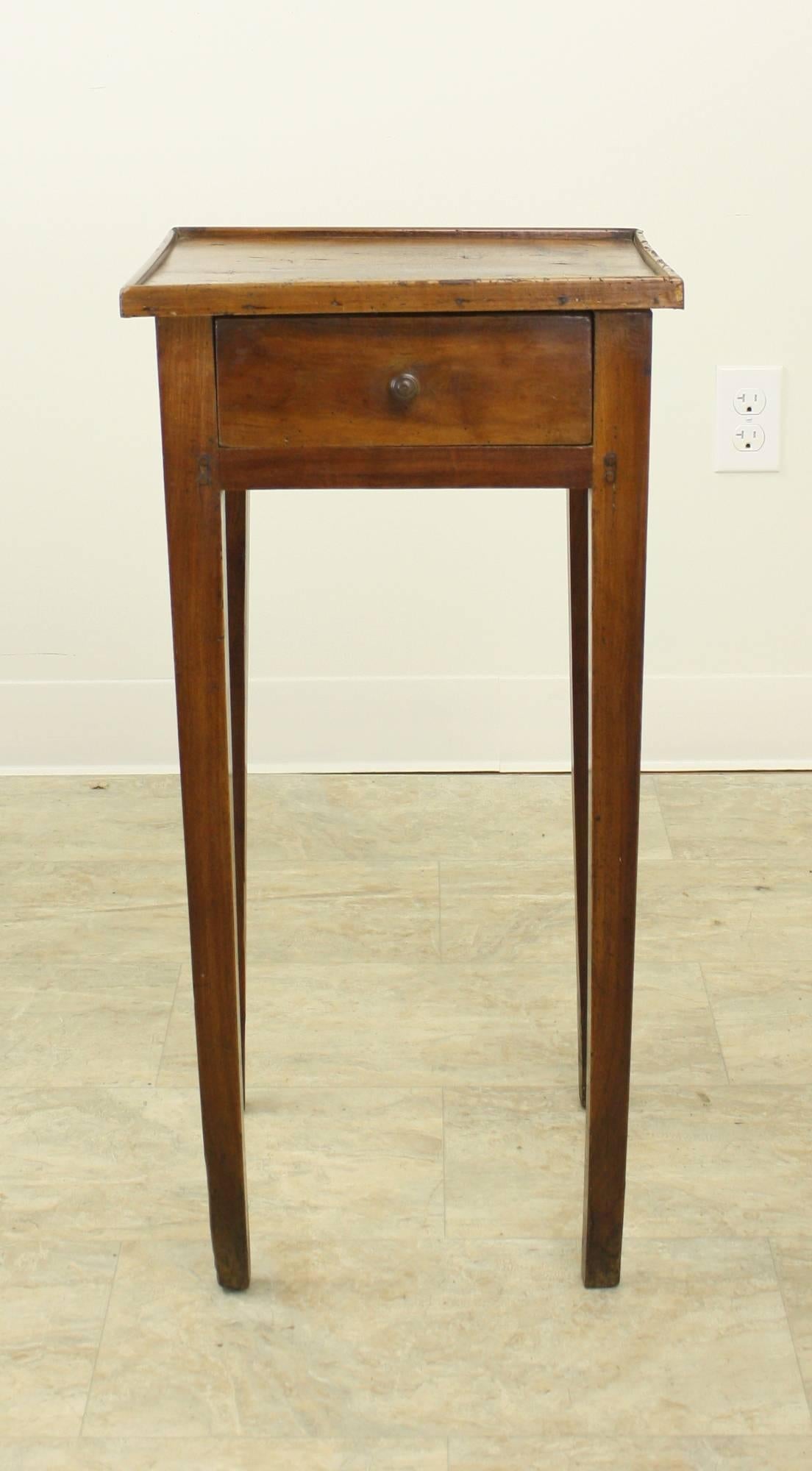 This is a delightful small table, with a charming little gallery on the top and a small drawer just under the top. The cherry color and the patina are warm and pretty. One sees two small old nail marks on the back of the top. Very nice slender legs