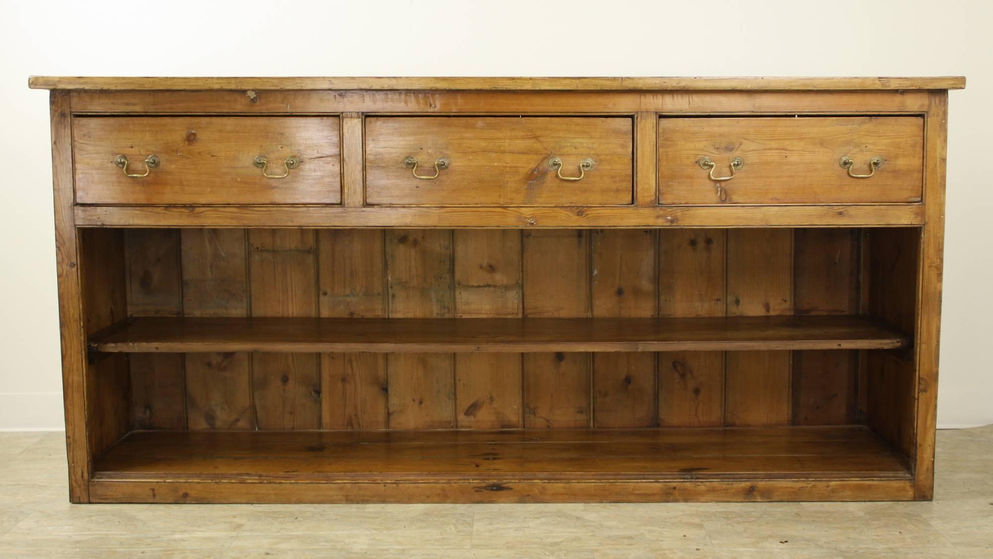This lovely, glowing, Georgian pine sideboard offers good storage on the shelves below the three large drawers. The good long length of this console makes it a very practical unit. An attractive moulding on the ends of the top is a nice finishing