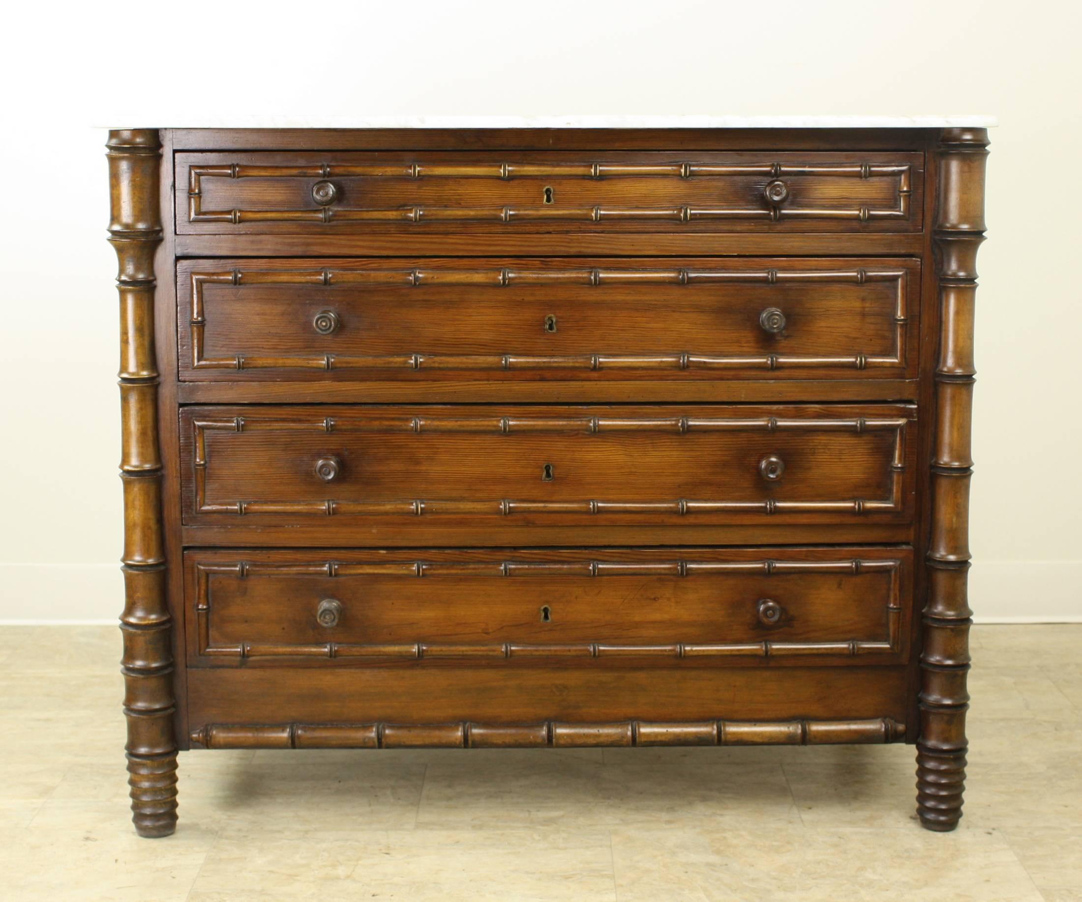 A charming French pine chest of drawers with faux bamboo turned molding, side columns and legs. Four clean and roomy drawers. The original white marble-top has been moderately resurfaced. Perfect for a bedroom paired with our other, almost identical