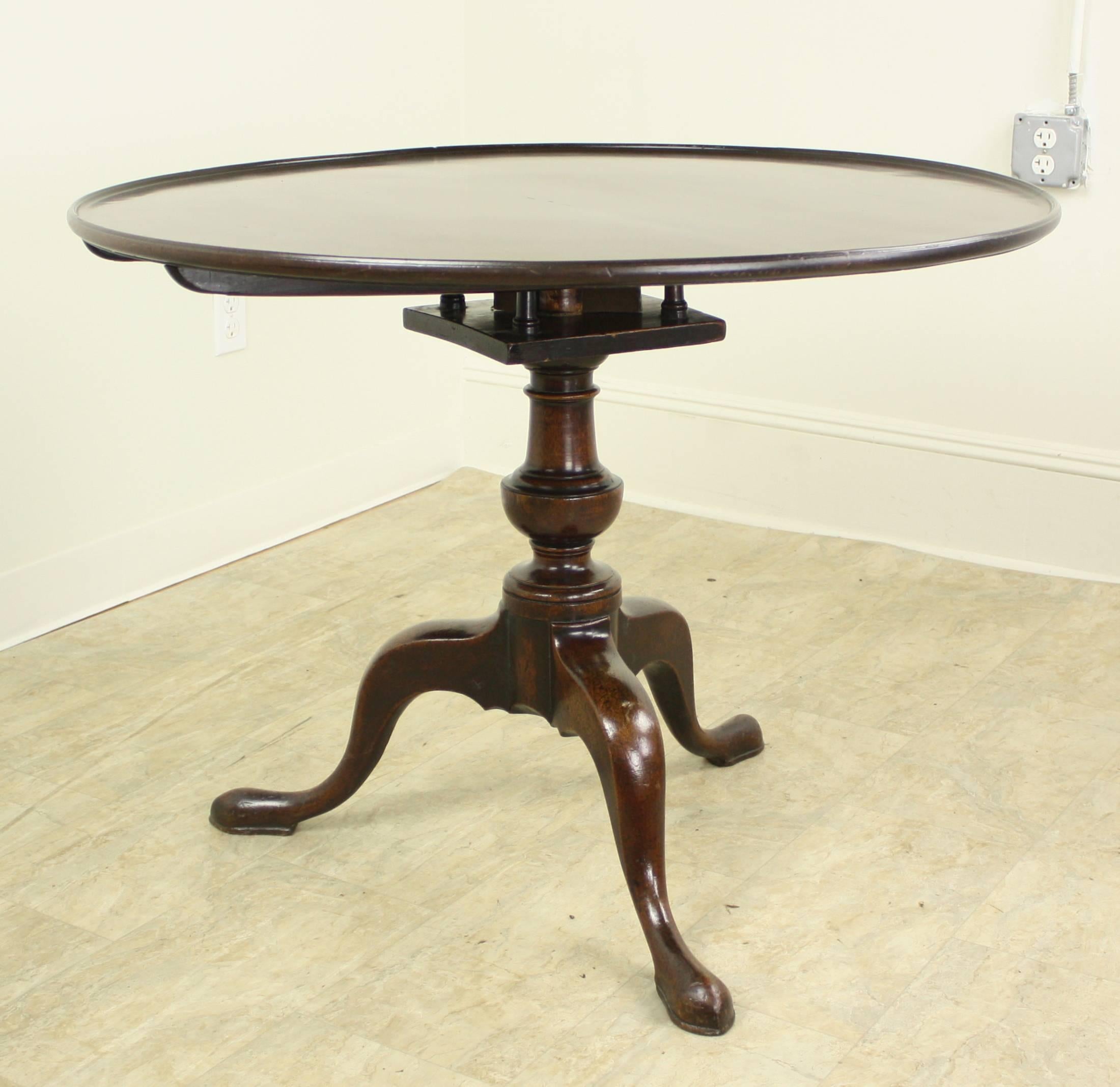 A fine Georgian tilt-top table, with a reeded dish top resting on a birdcage base. The lovely baluster-form pedestal, complete with vase turned shaft, ends with graceful cabriole legs and pad feet. Slide button mechanism insures a secure fit in the