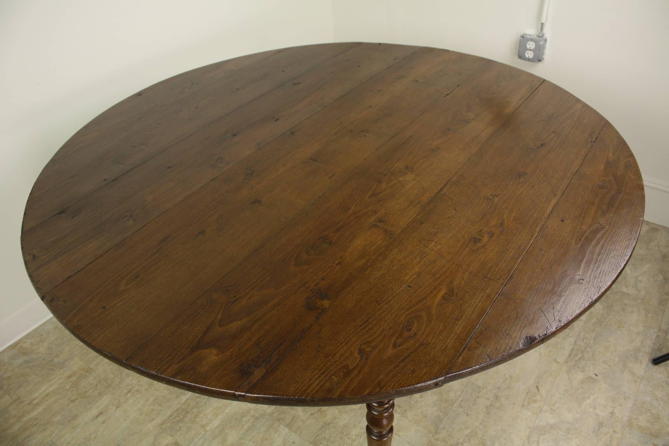 An almost perfect round dining table in laburnum wood, with elegant turned legs and brass castors. The top has rich color and lovely patina. The base is inset enough, 11