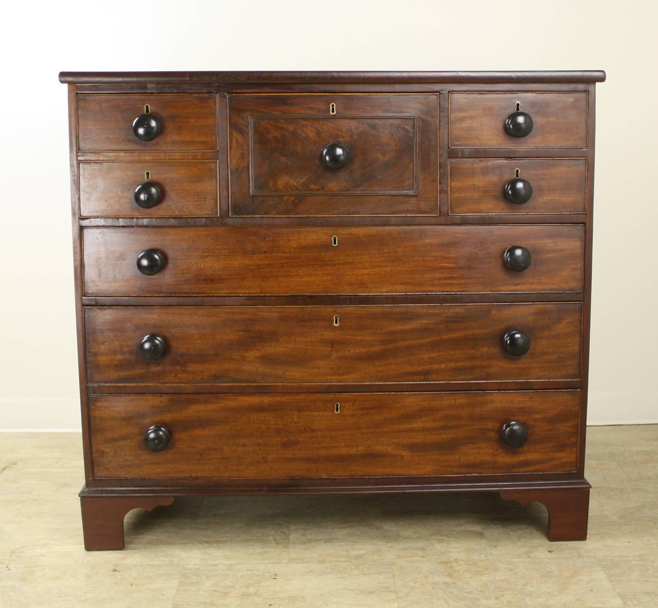 A splendid mahogany chest of drawers, with one deep center drawer, a faux double compartment to the left and two small ones to the right. All on top of three roomy lower drawers. Unusual, beautiful, and lots of storage to boot! The mahogany is in