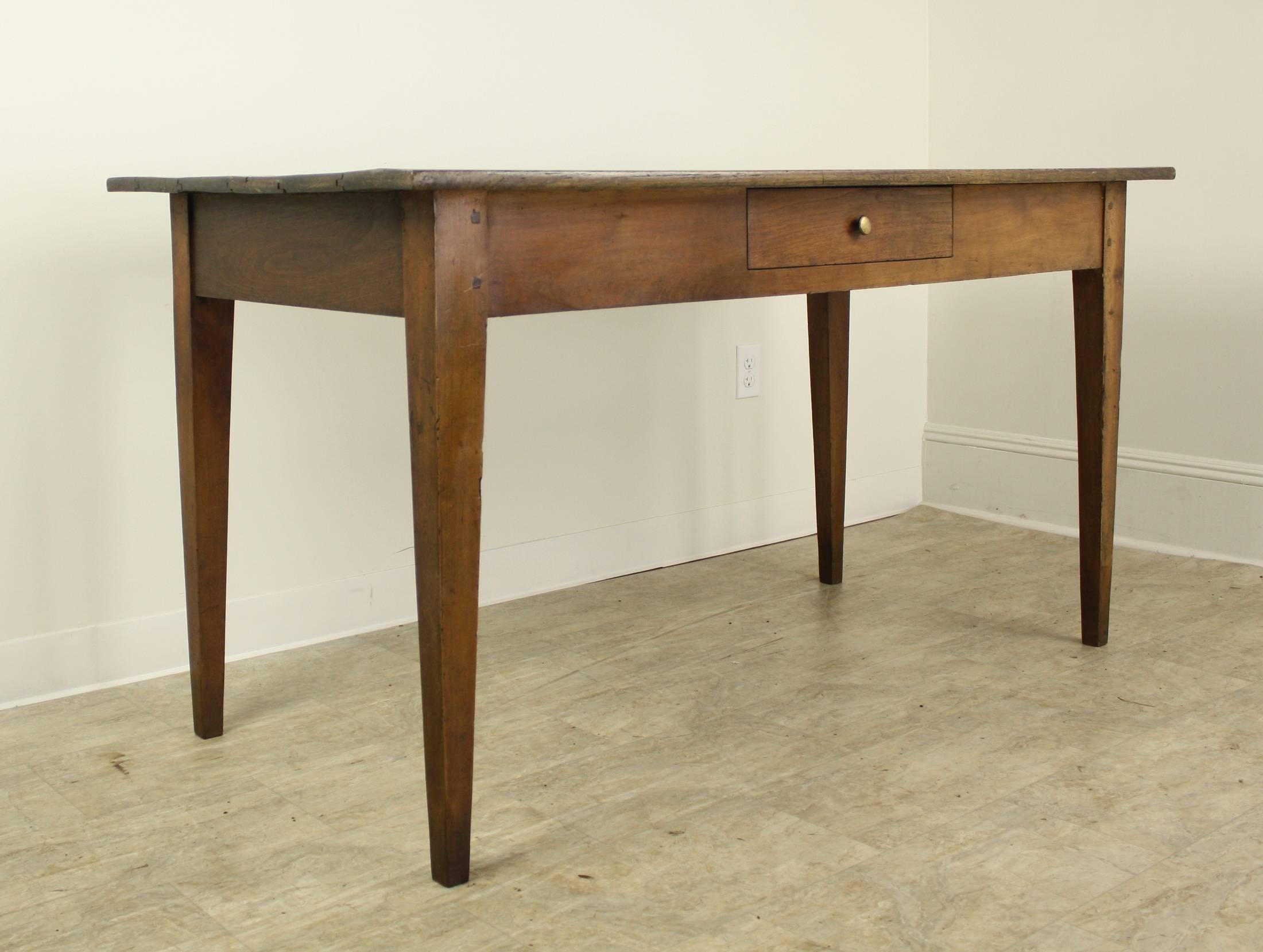 A pretty French writing table with a mellow chestnut top, nicely distressed and patinated. Tapered legs are pegged at top, and the single drawer draws the eye to the piece. 24.75