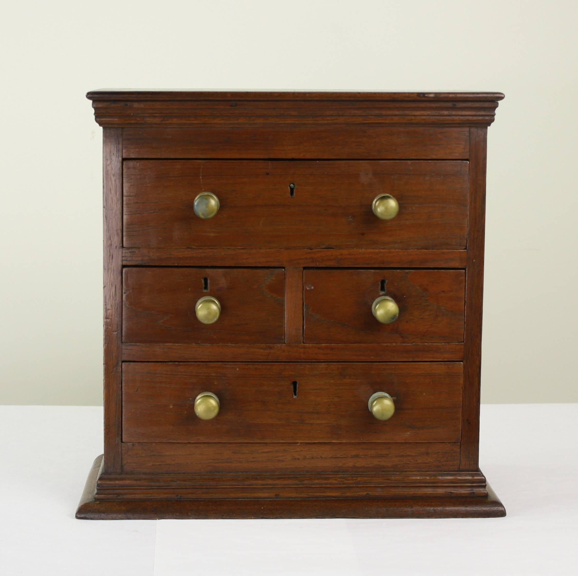 A beautifully fashioned little chest of drawers in teak. Handsome mouldings at top and bottom and lovely antique patina. Great for jewelry or as a decorative conversation starter. Possible apprentices' practice piece.
