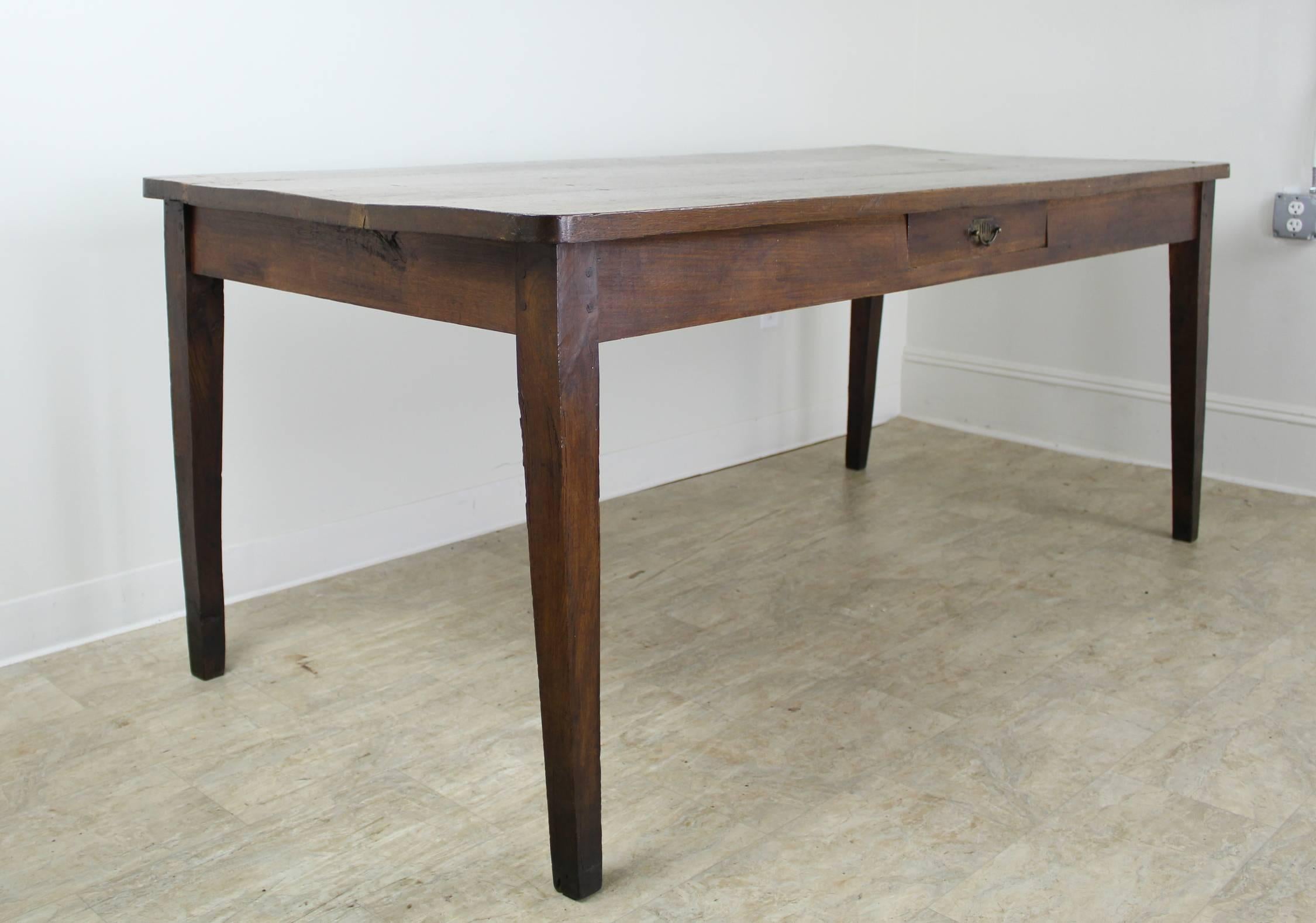 A handsome dark oak farm table with a chunky top and decorative handle on the single drawer. The piece displays beautiful color, grain and patina. Good depth for serving. The apron height of 24.75 inches is comfortable for knees.