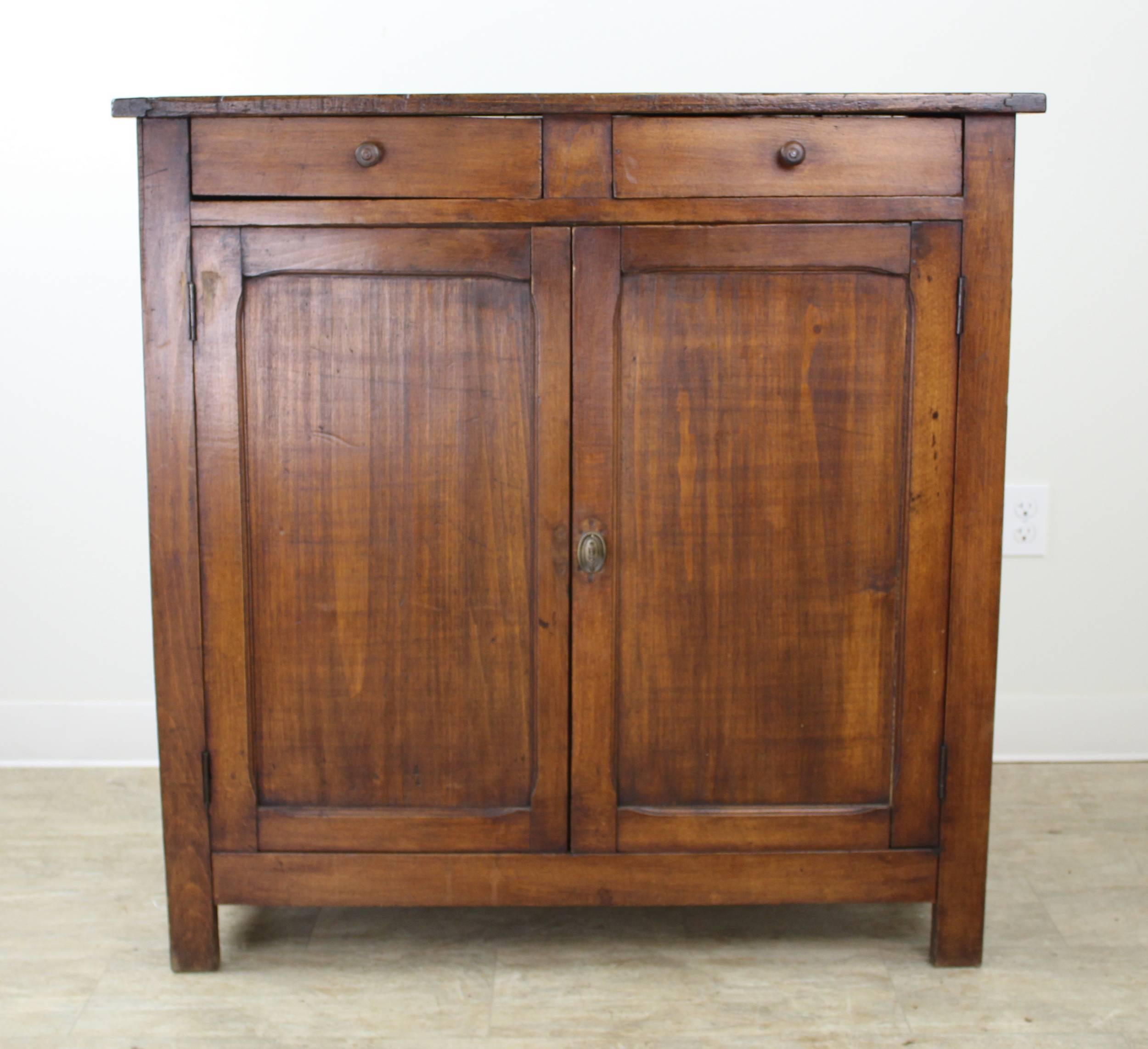 A tall, slim fruitwood server, sideboard or buffet from France. Two roomy drawers atop a two shelf cabinet. The lock and key are in very good working condition. Inset panels with carved edges, as seen in image #8 add attractive detail.