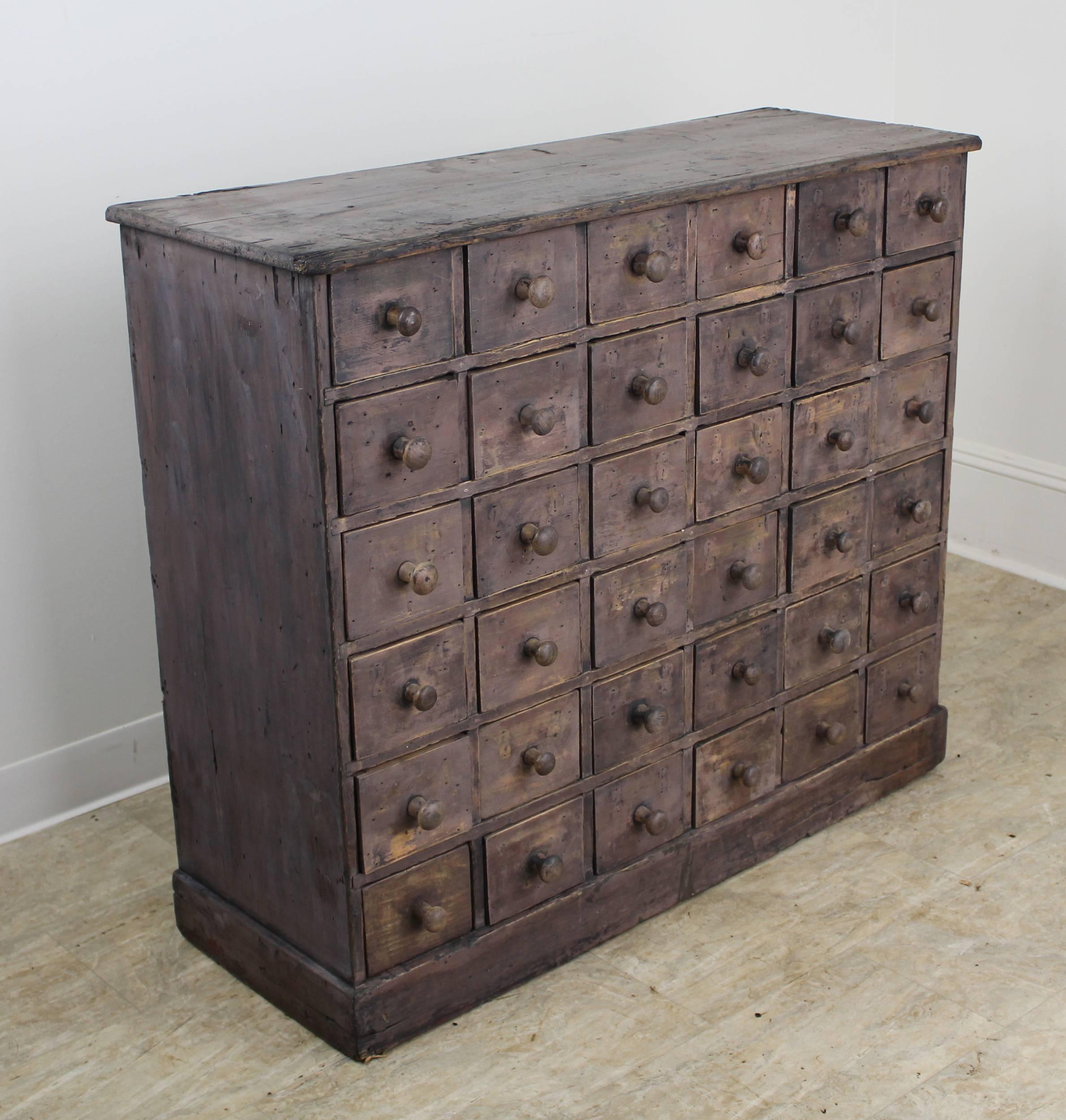 A French apothecary chest with original grey/violet paint and fabulous interesting distress. The drawers are all consistently clean and slide easily. The back of the piece is unfinished A new back can easily be added but the piece is completely