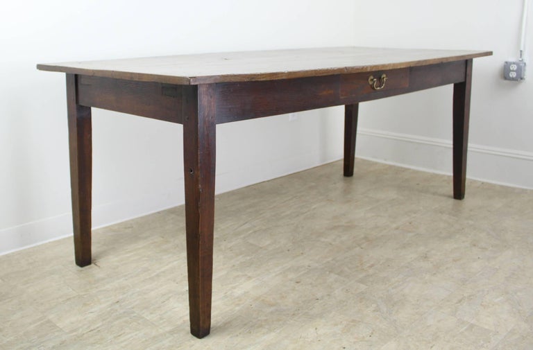 A great looking farmhouse table, with good color and patina on top, and a lovely grain. With very little distress. A charming small knothole is just off center on the top. The single drawer at the center of the apron adds a note of interest. Good