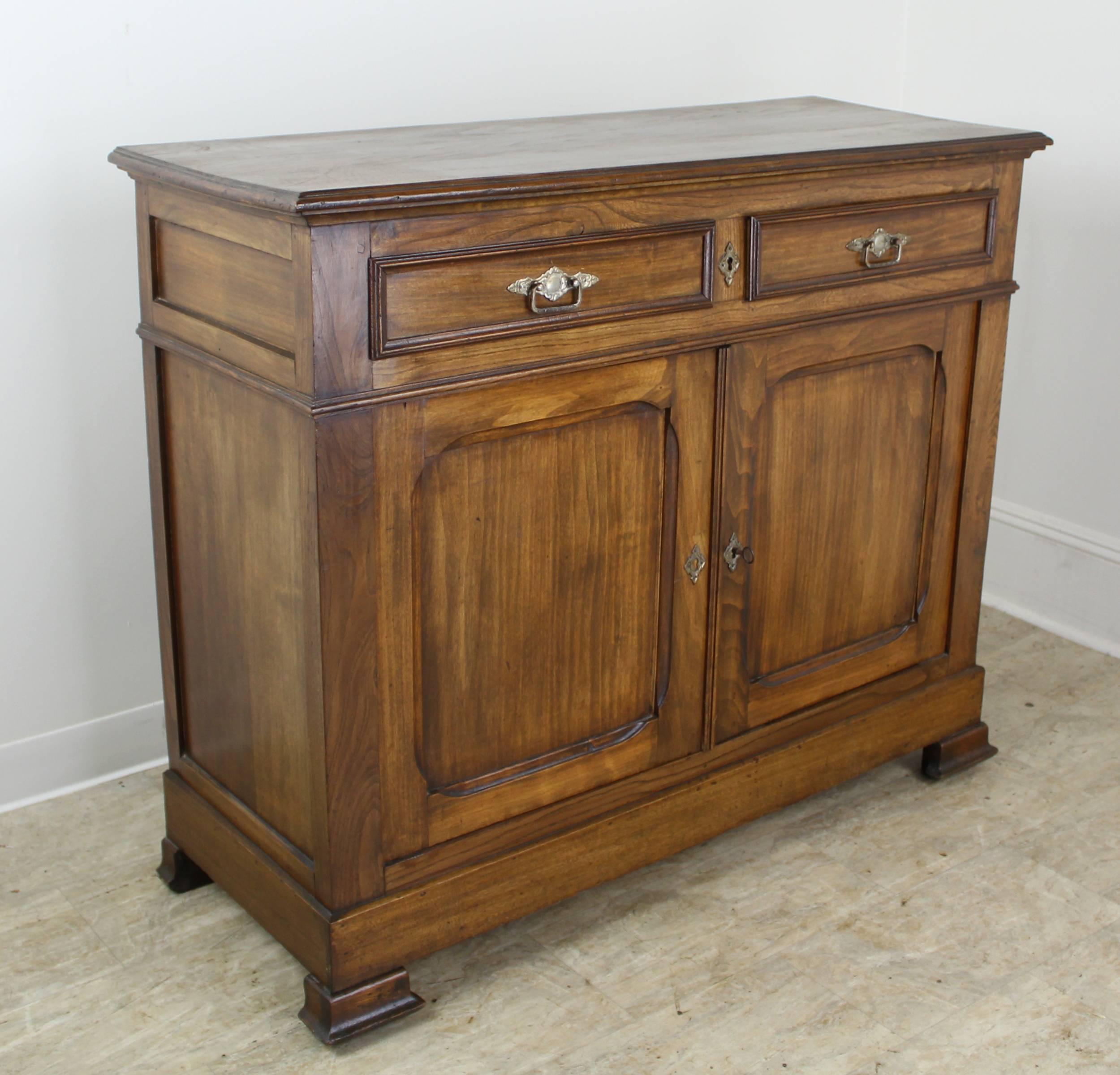 A classic two-door buffet in dramatically grained elm. The eye catching design details include interesting molding at the top, carved inset panels on the doors and sides, and classically shaped feet. The single interior drawer is non-adjustable.