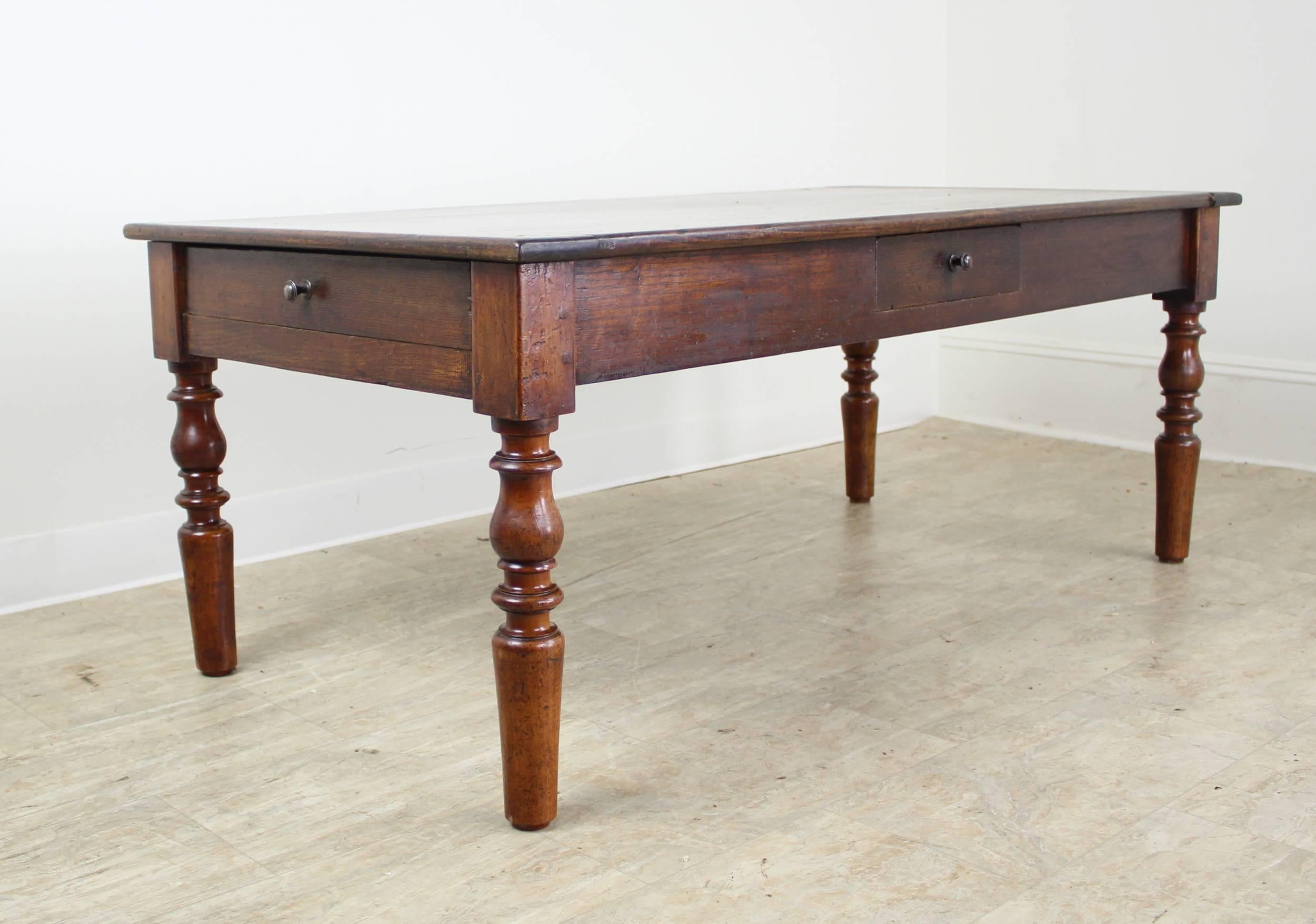 A handsome antique chestnut and fruitwood coffee table. This table boasts three drawers and a pull-out serving shelf, originally a bread slide. The chunky turned legs lend a charming design note. Breadboard ends on the top accent the richly grained