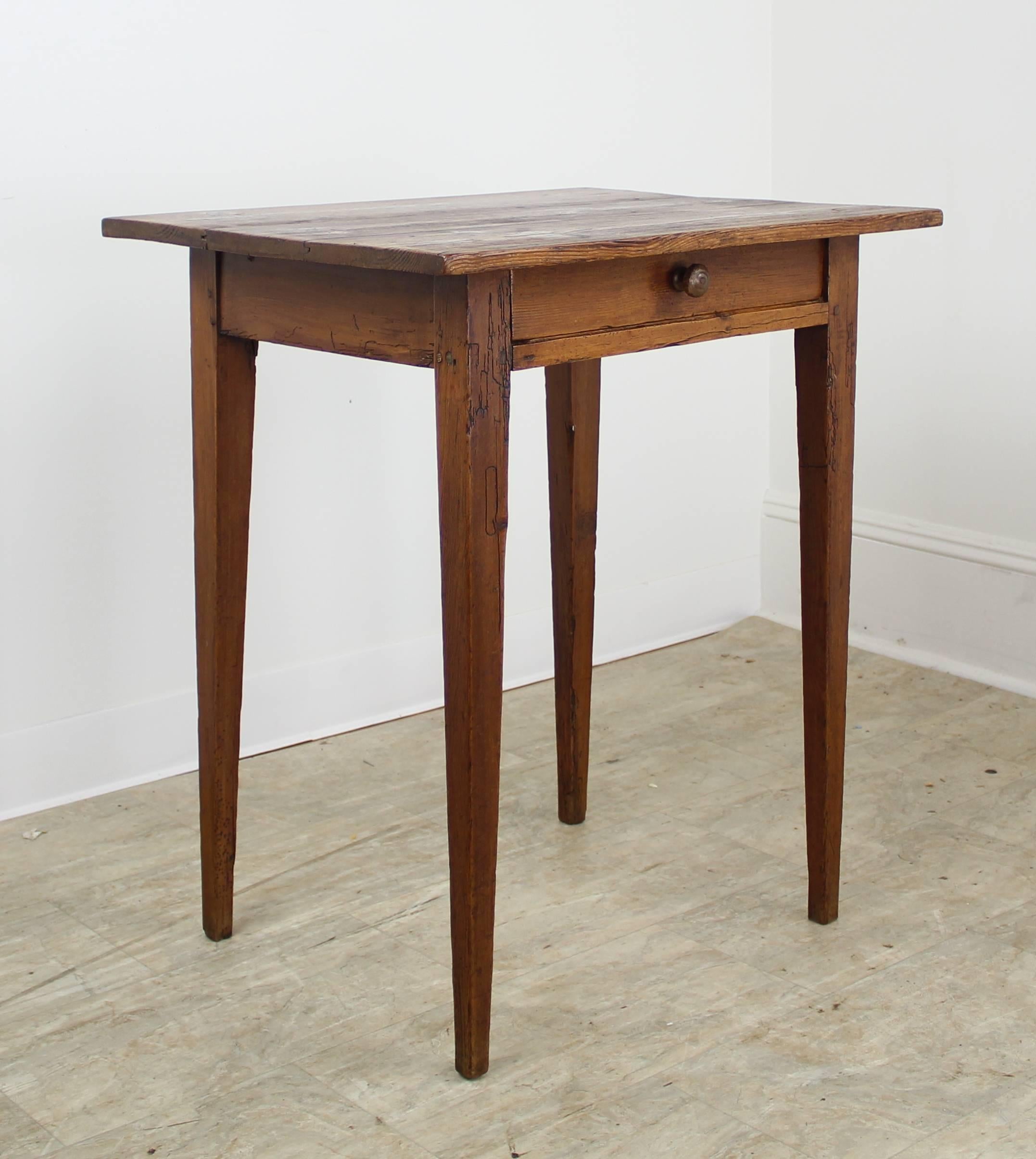 A pretty pine farm table with a charming small size, rich color and nice patina. The single center drawer and sweet tapered legs give the piece universal appeal. The top has nice interesting distress.
