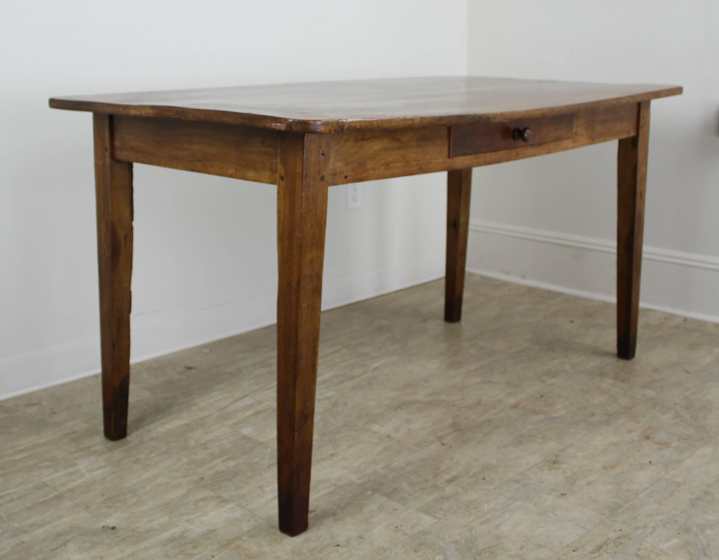 A chunky cherry farm or writing table with lovely color, grain and patina. Pretty tapered legs and a Classic look. There is a slight bow on the top which adds character and does not greatly impact the levelness of the piece. A pencil, placed to one