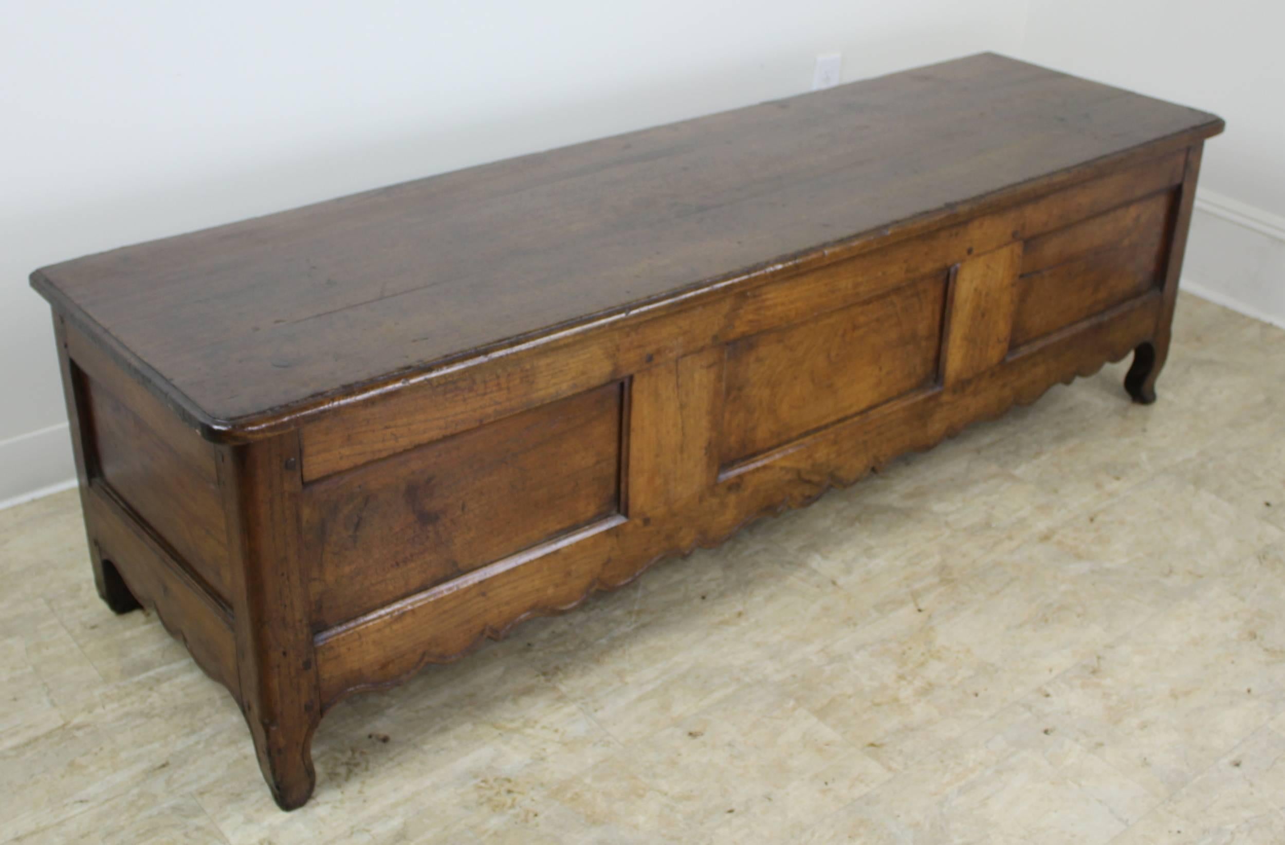 A pretty chestnut coffer or bench with a hinged top and plenty of storage within. Charming carved apron and good color and patina. This piece would be right in the end of a bed, in the entrance hall, or well-appointed mudroom.