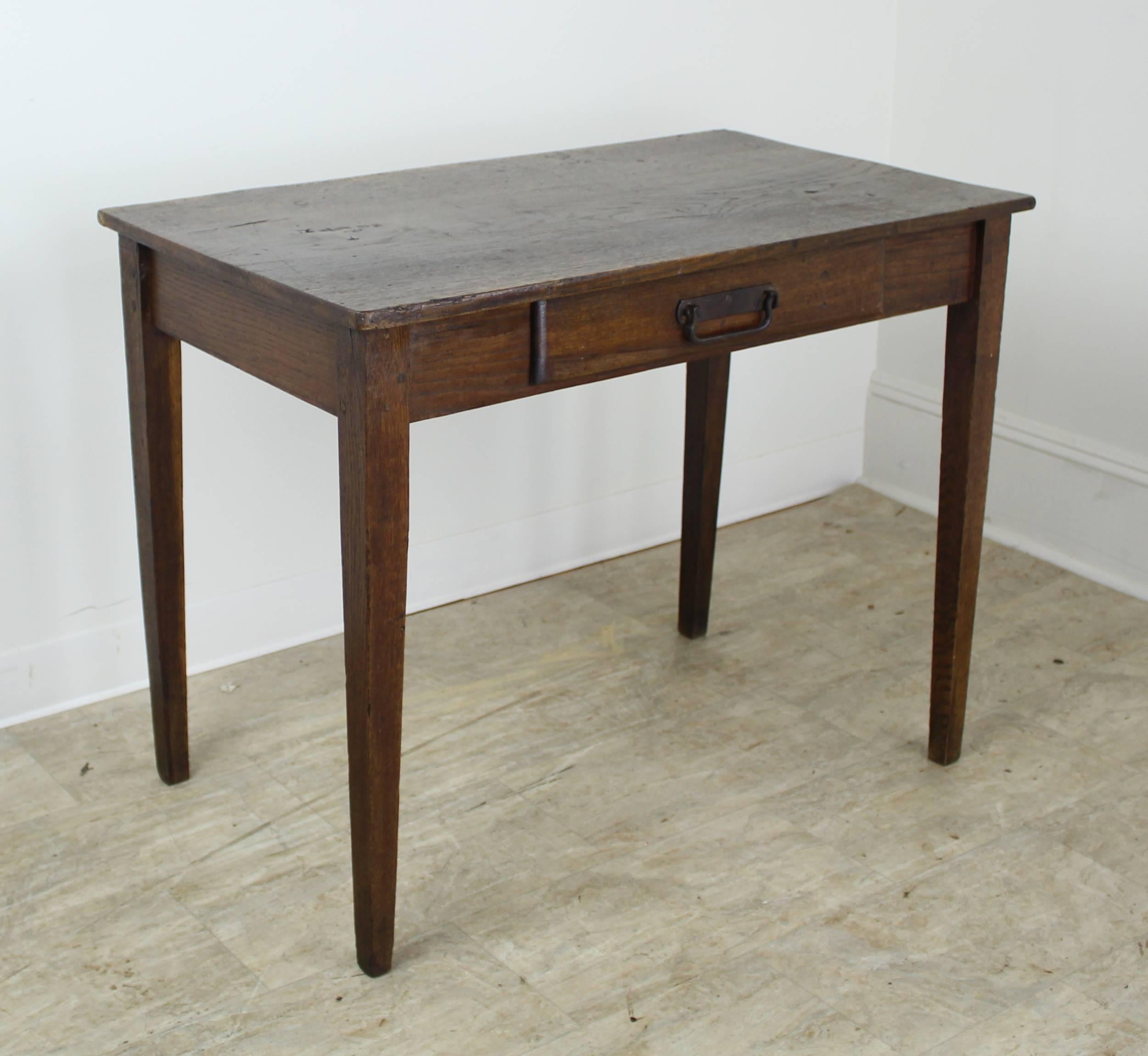 A handsome, slightly narrow dark oak side table fashioned from a single plank, complete with nice grain, rich color and fine patina. Tapered legs and one centre drawer.