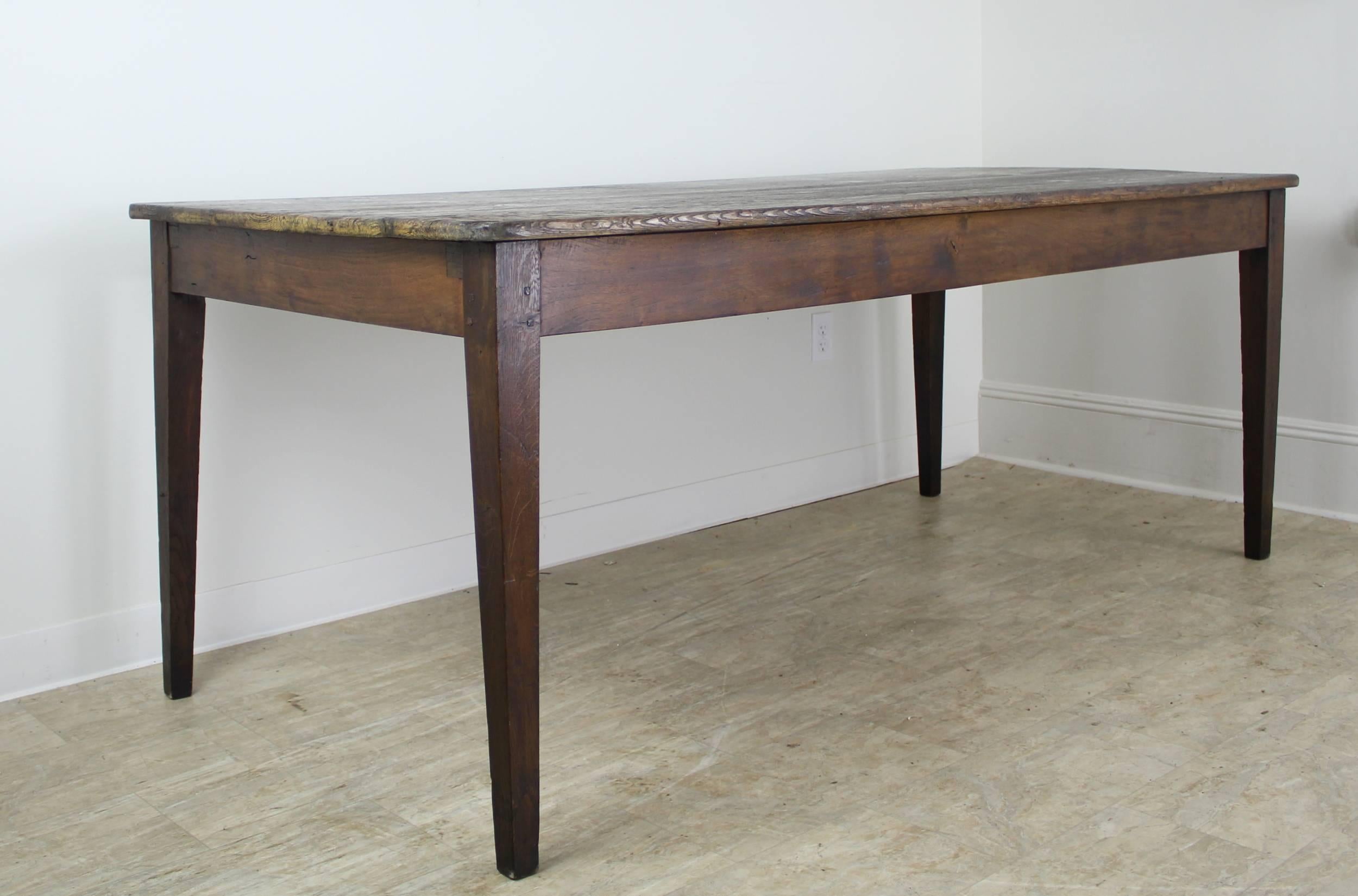 A sturdy handsome pine farm table with a scrubbed top, full of character. This table has great depth for accommodating eight place settings, and a turkey in the middle! Elegant tapered legs pegged at the top. A 24.5 inch apron height is good for