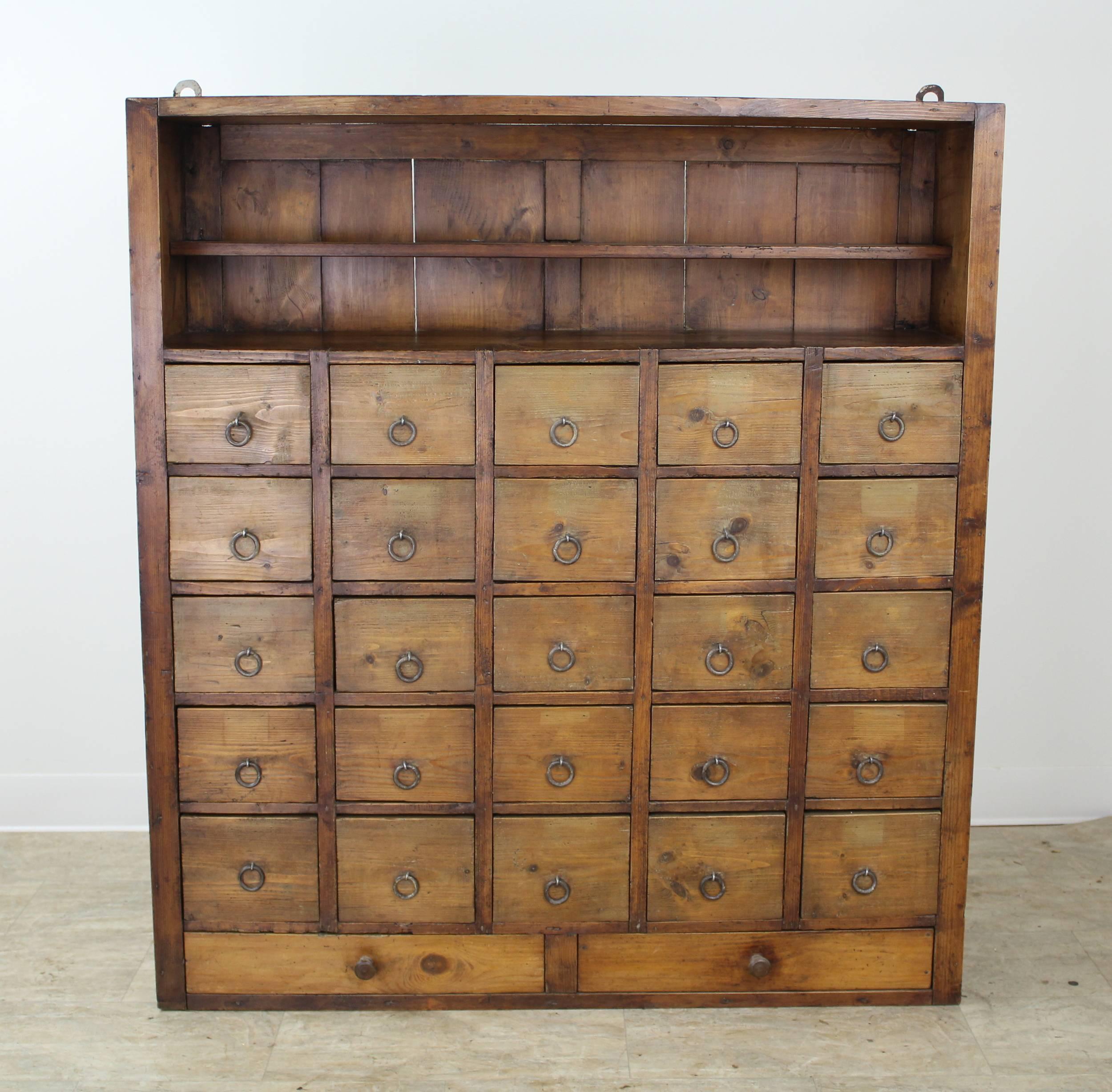 A bank of pine drawers from 19th century France, in a warm honey color with wonderful patina. Originally wall-mounted, probably in a country apothecary, this piece retains its original brackets which can be easily removed, or kept for mounting. The