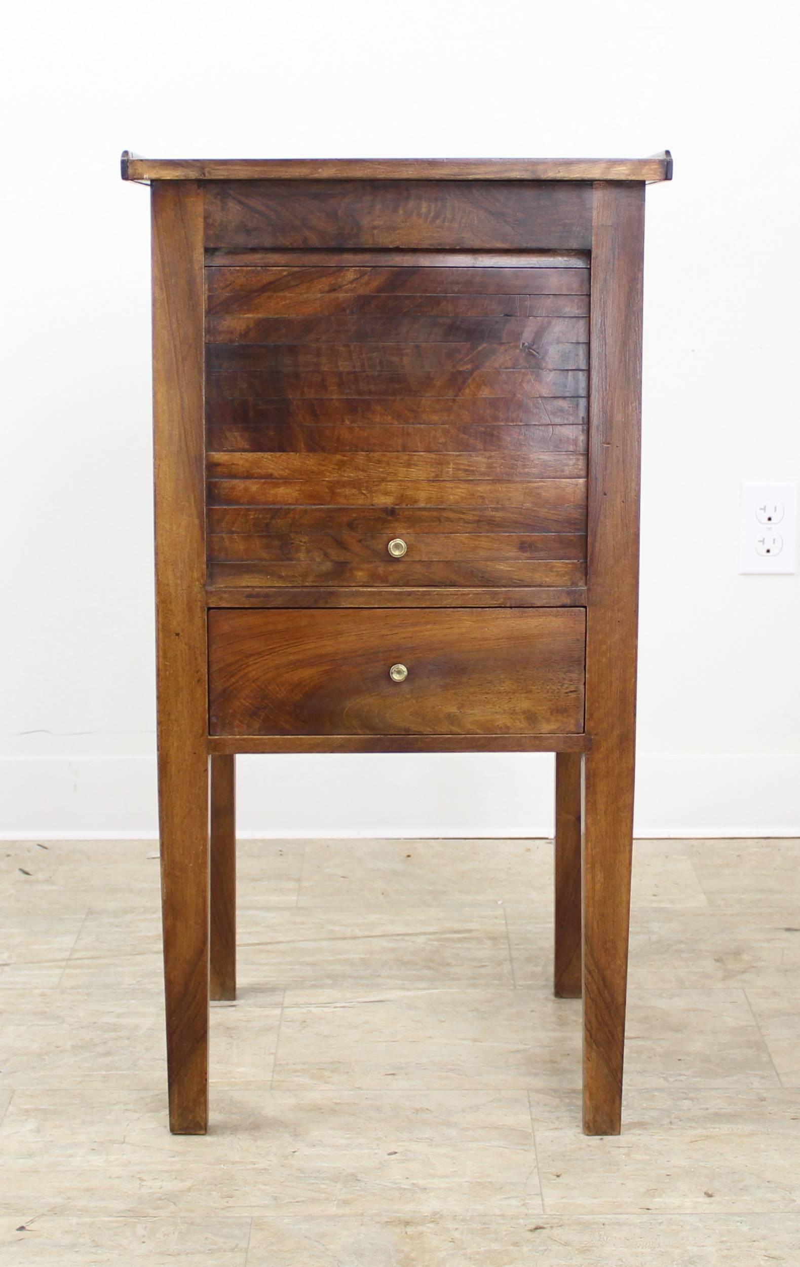 A charming elegantly scaled antique bedside cabinet from France. Made of walnut with a beautiful color and rich patina. The tambour front rolls up for interior storage. Would work next to a bed or as a side table or end table in a smaller space.
