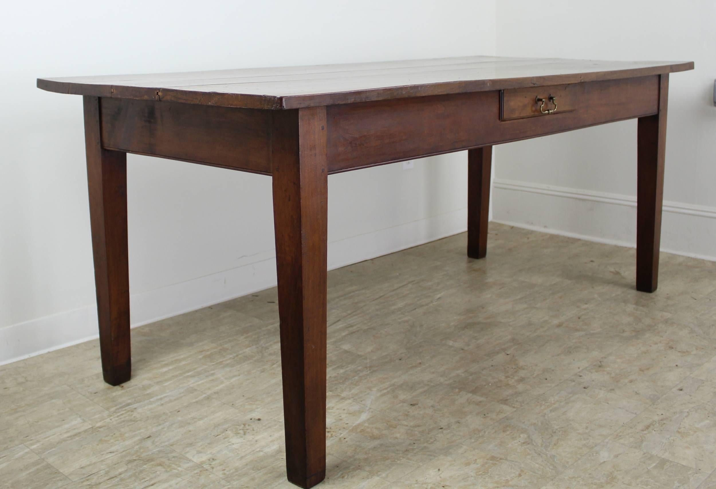 Very handsome dining table with lovely shine and interesting grain. Apron height is 24.25 inches. One nice drawer in the front long apron. Classic French tapered, slender legs. Lovely warm color and patina. Distance between the legs is 62.5 inches.