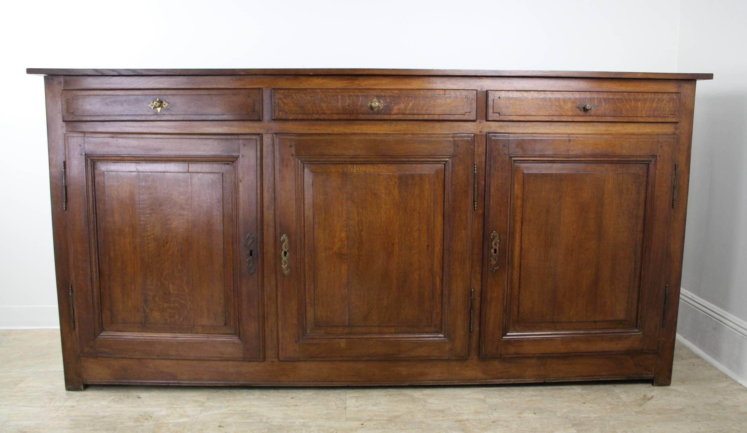 Dramatic piece with great storage in three shelved compartments with three drawers above. The doors are well panelled as are the sides. Warm dark color and nicely patinated grain. There is a simply shaped apron. Long door hinges and escutcheons are