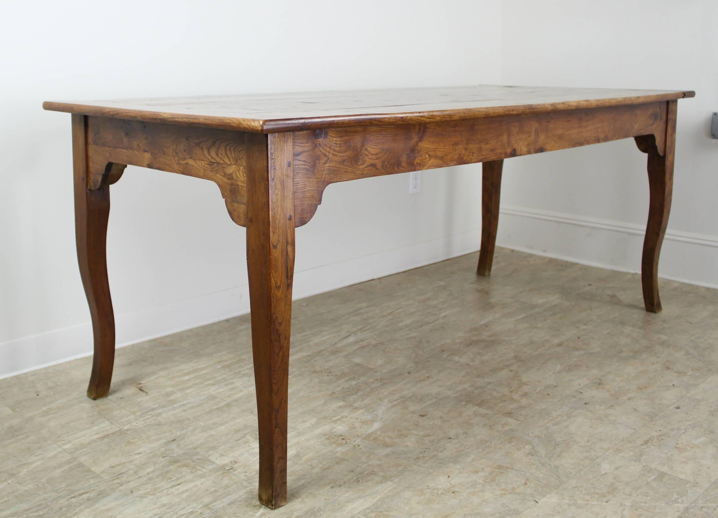 This is a Classic country dining table, more formal than a traditional farm table and made with the most beautifully grained elm we have seen. The lovely profile features graceful legs, breadboards ends on the top, and pretty supports at each