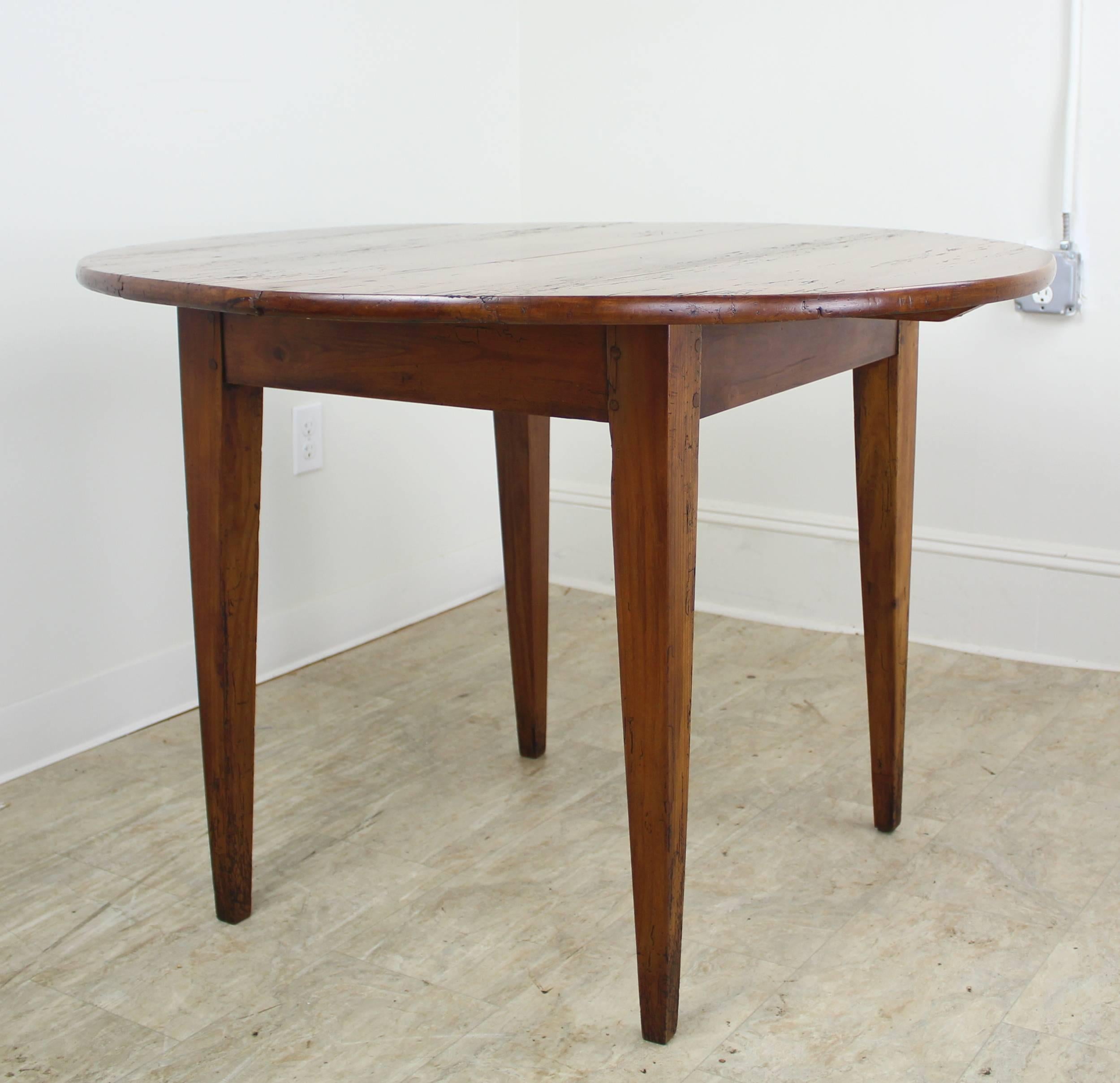 An antique thick topped breakfast farm table from France. Made of cherry with a rich color and patina, with areas of moderate distress. A good-sized breakfast table. Very good for small dining table. Lovely farm table tapered legs. Note that the top