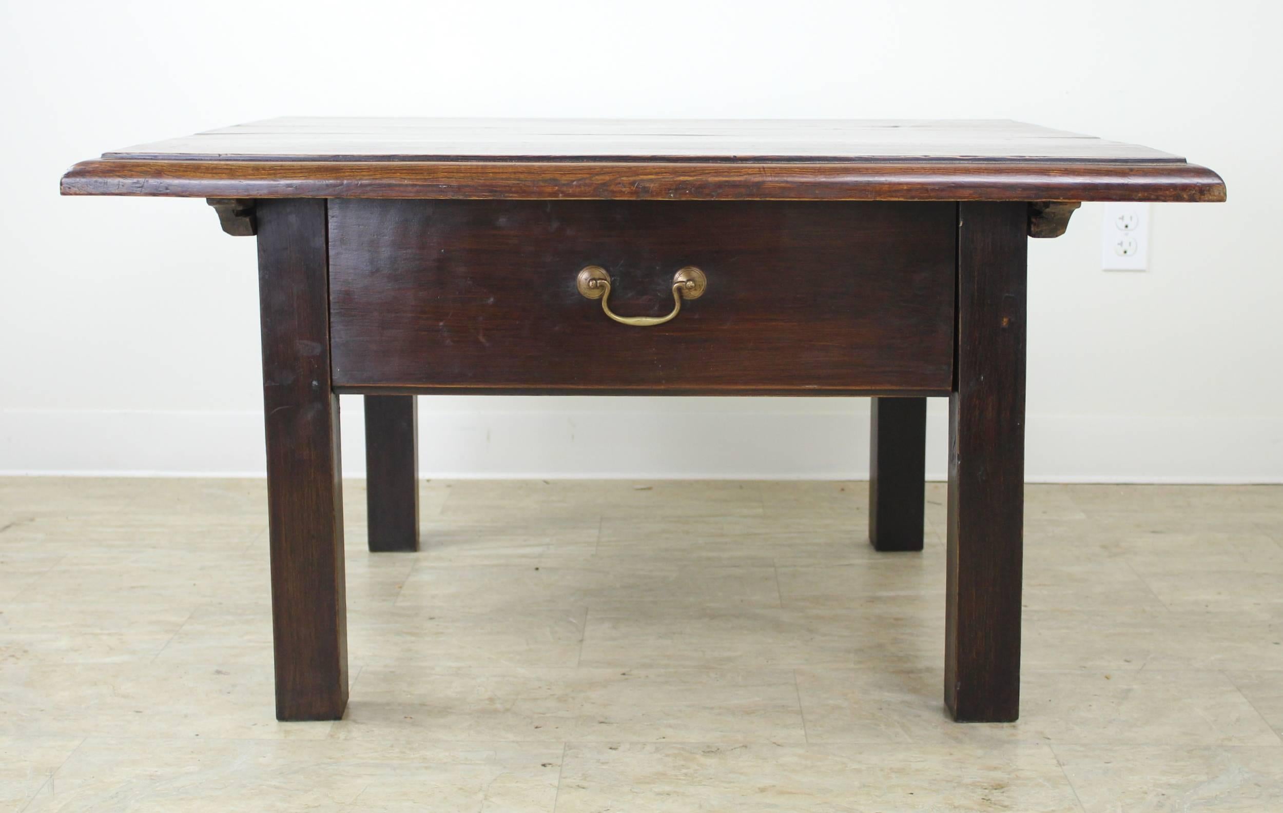 A dark elm coffee table with rich color, good patina, and a twist. This coffee table has a floating top that slides back and forth to reveal a secret compartment. Perfect for hiding valuables! The facade of the compartment has a brass escutcheon