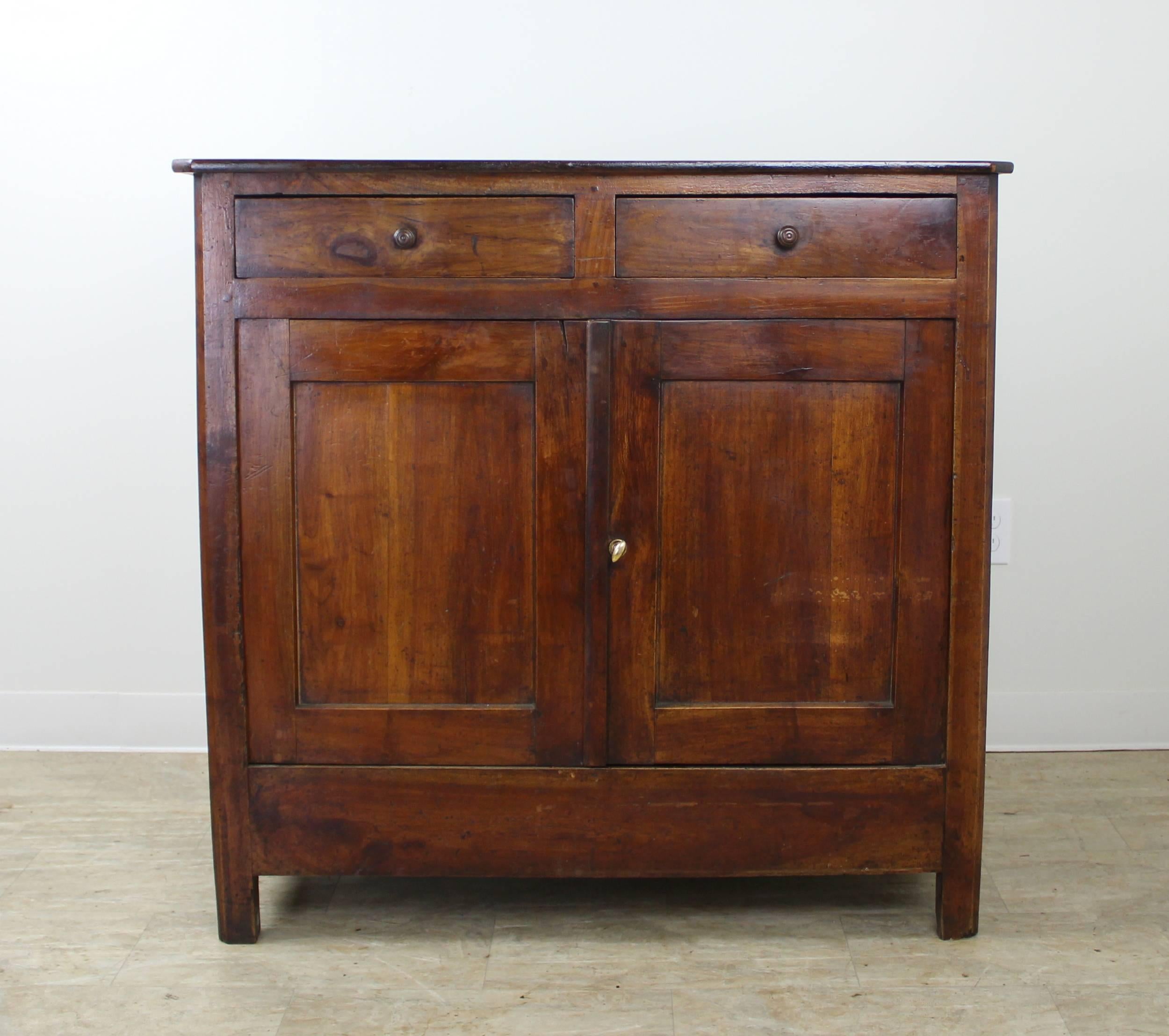 A tall cherry server, sideboard or buffet from France. Two roomy drawers atop a two shelf cabinet. The top has canted corners and lovely color and grain. There is a slight warp at the top of the right door which does not affect its ability to close