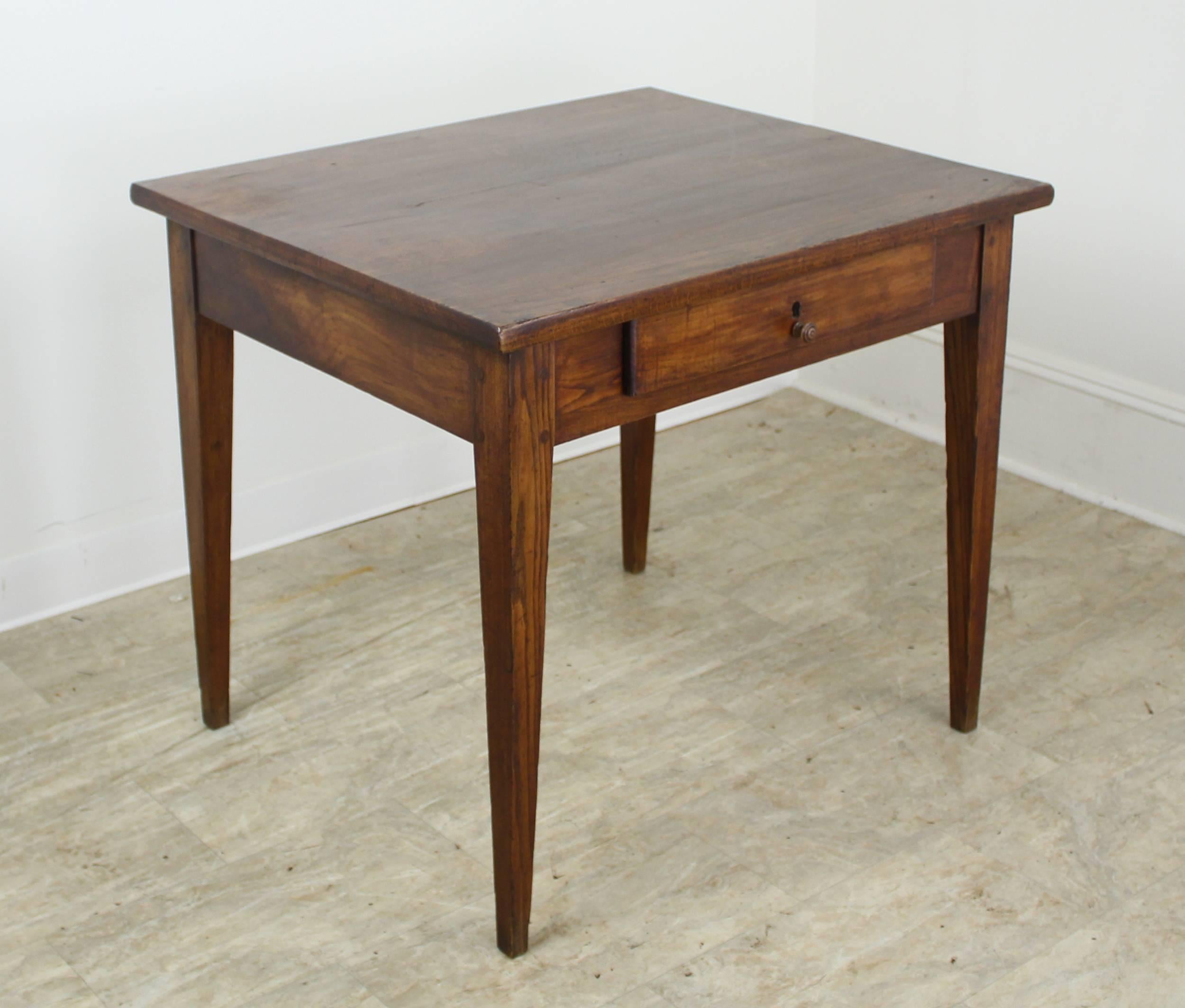 A small elm farm table with a chunky top and traditional tapered legs with single drawer. Good color and patina. Classic.