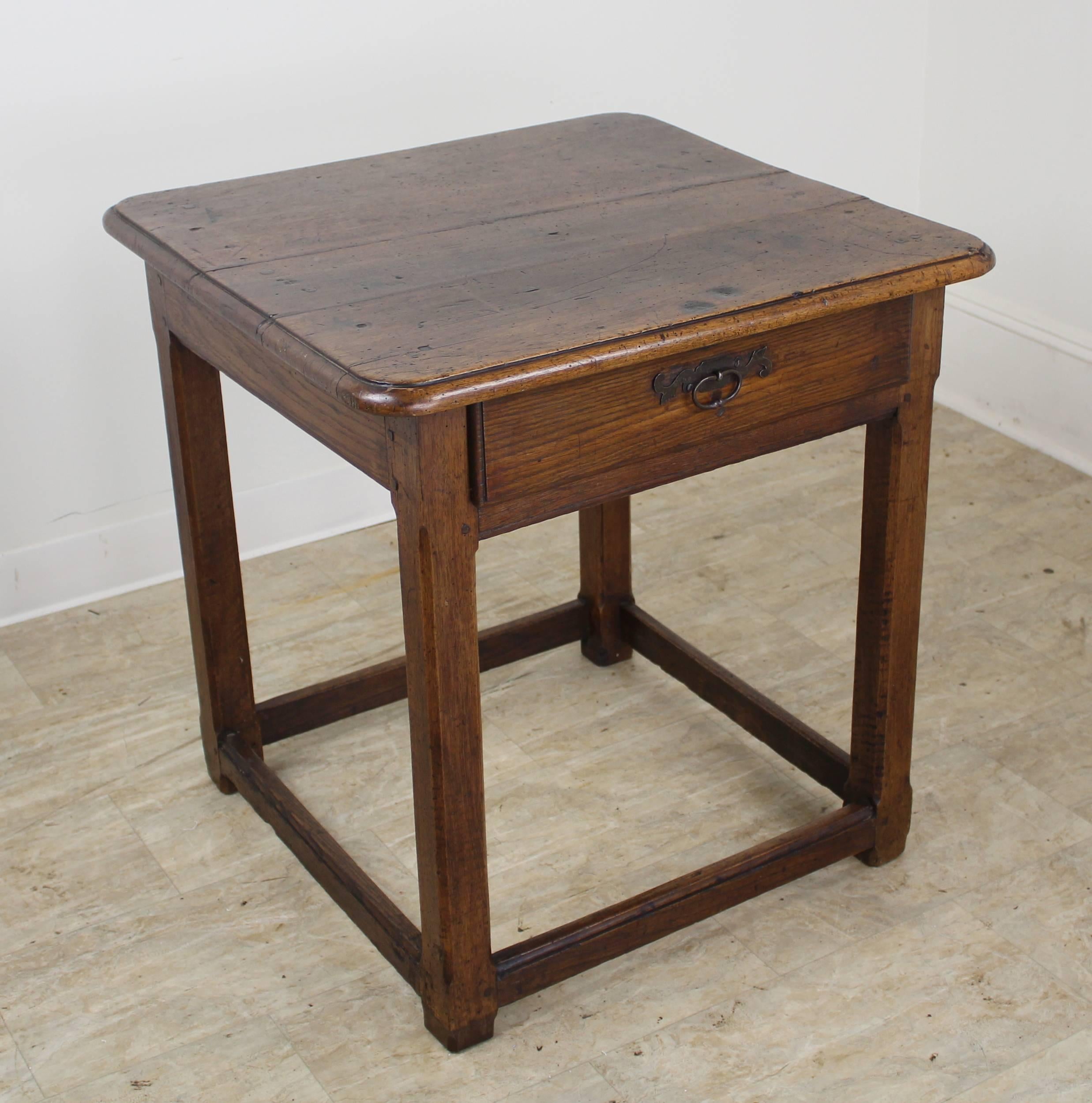 A handsome early walnut side table with original iron hardware and a stretcher base. Wonderful dark color and good patina. Would make a good lamp or occasional table.