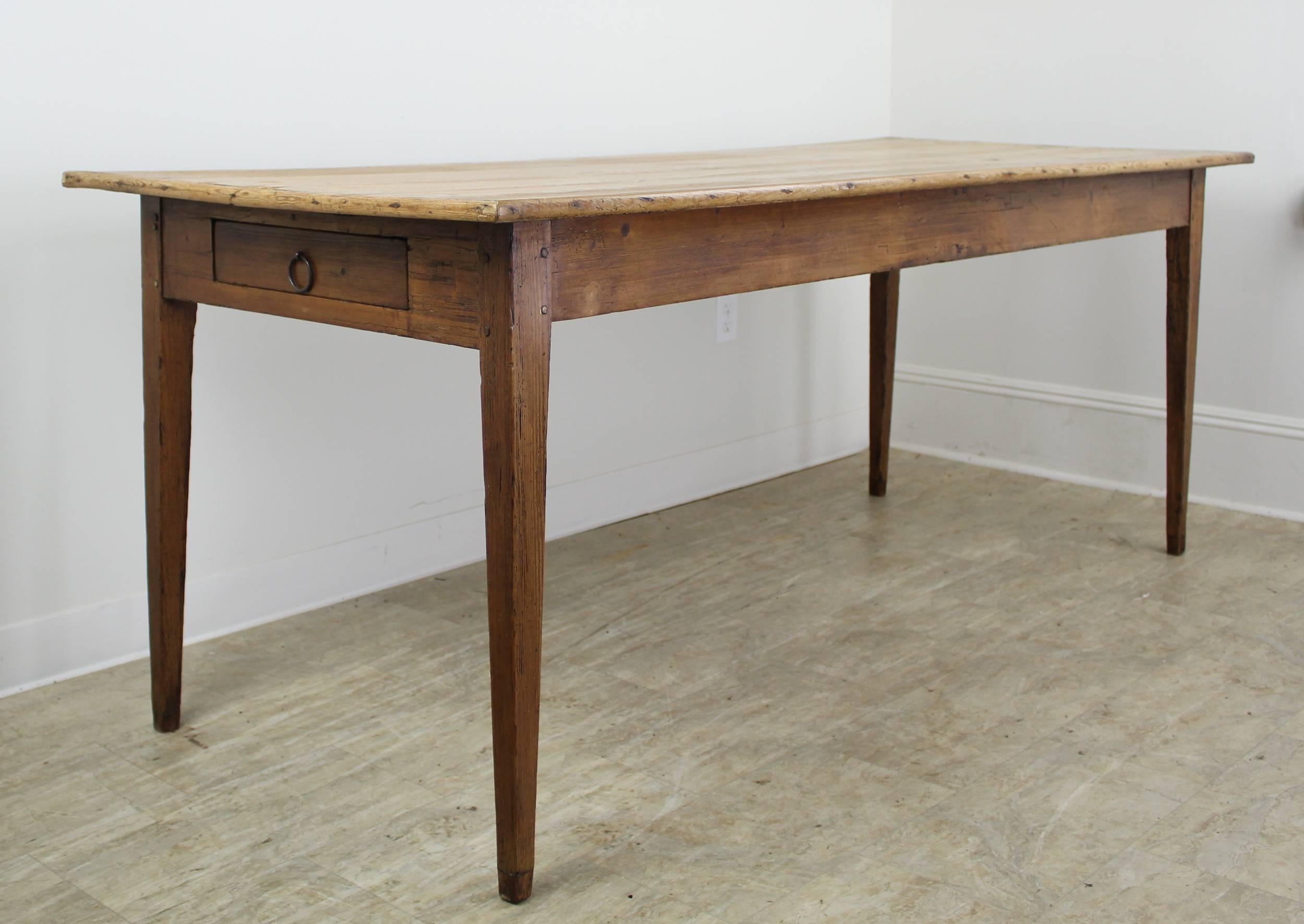 A graceful very light pine farm table with a decorative edge and rustic appeal. Fine naturalistic features and full grain bring loads of character to this simple country piece. The top and legs boast fine patina. 25 inch apron height is good for