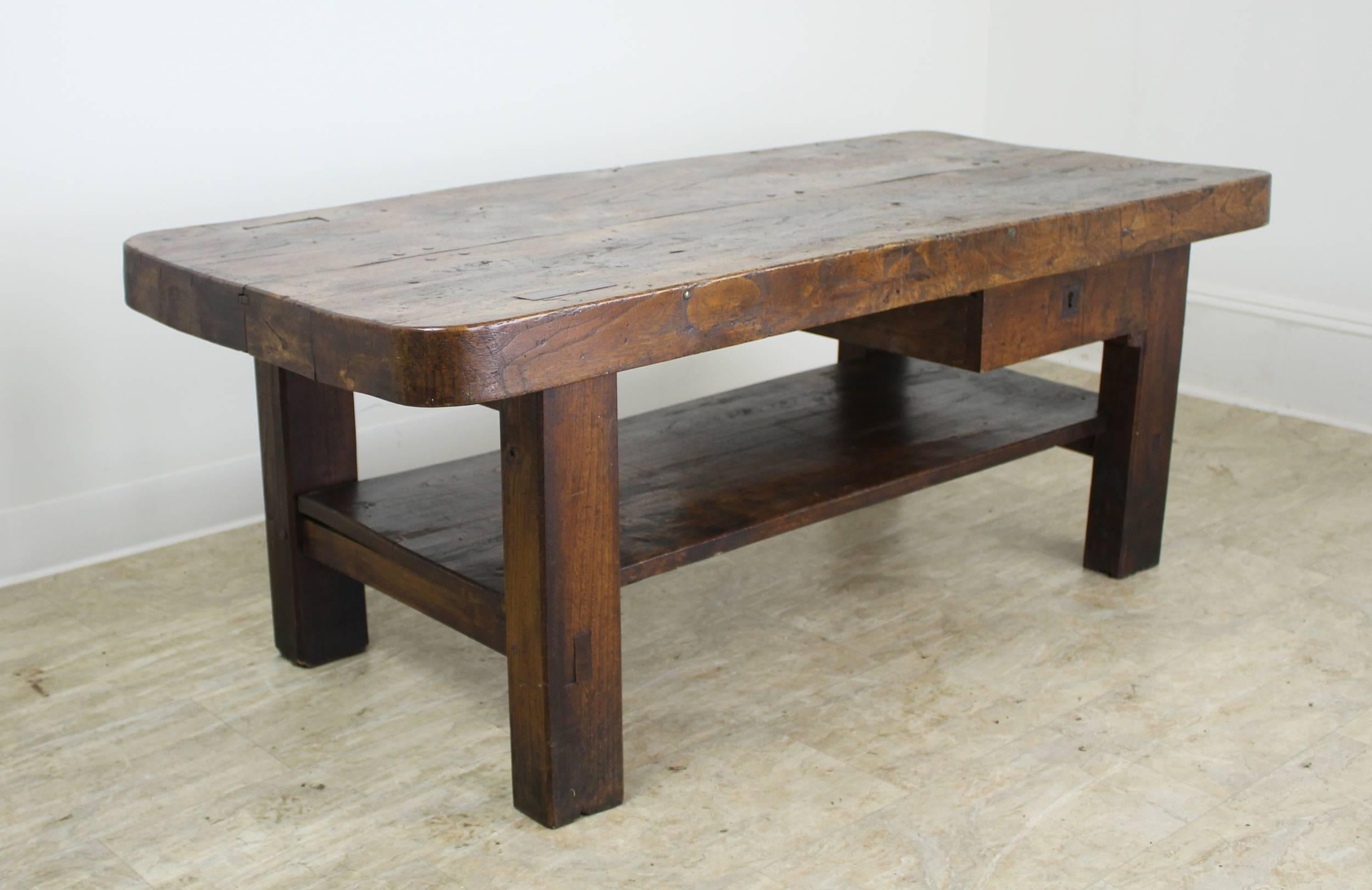 A handsome sturdy French coffee table with a 3 inch thick top made of solid burr elm. The top, with its fanciful grain and patinated shine, is the eye catching center of this piece. The drawer has a fully functioning lock and key, with a secret