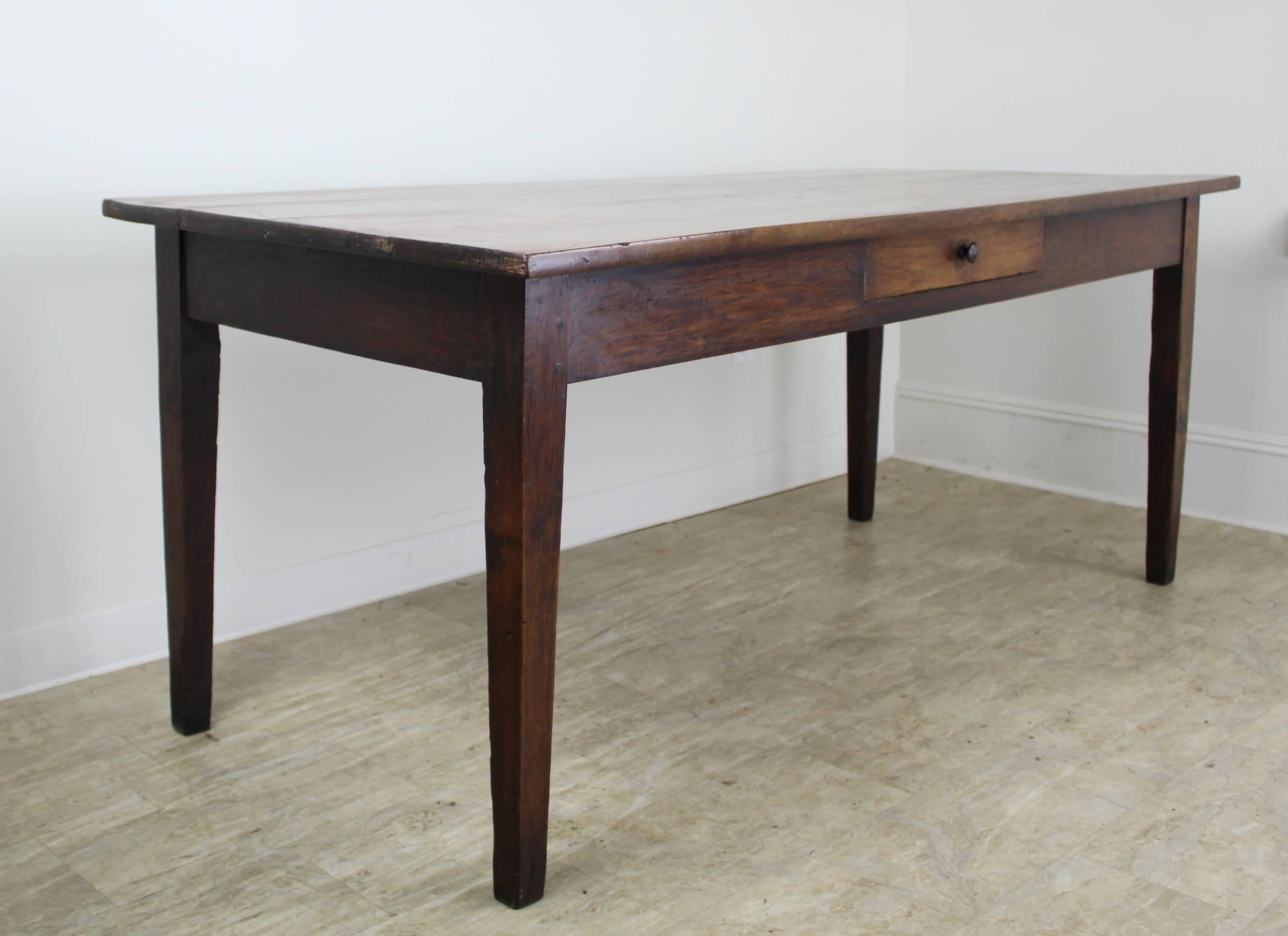 A smaller cherry farm or dining table with a thick top. The color and patina are very good, with a warm glow. 24 inch apron height is good for knees, and there are 63 inches between the legs on the long side.
