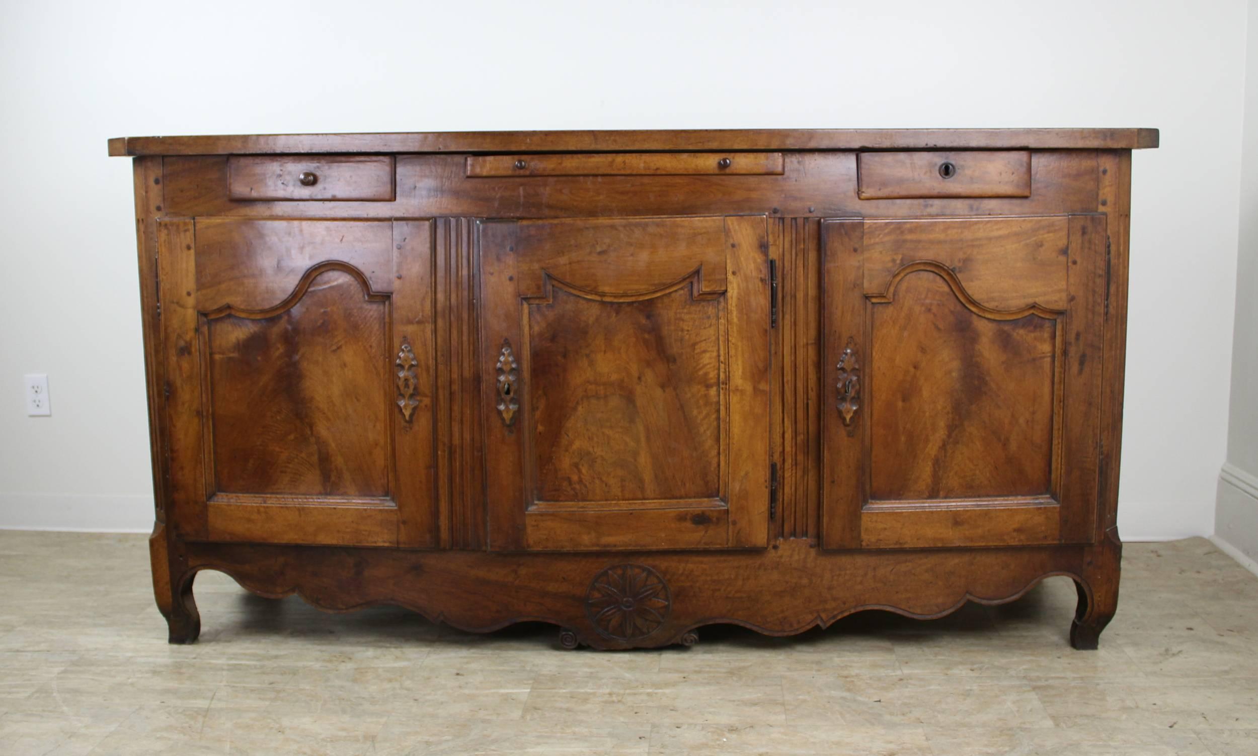 A handsome and imposing French walnut enfilade with interesting design detail and decorative carving at the well shaped apron. Graceful carved wood escutcheons and decorative reeding at the corners add another degree of period design interest. In