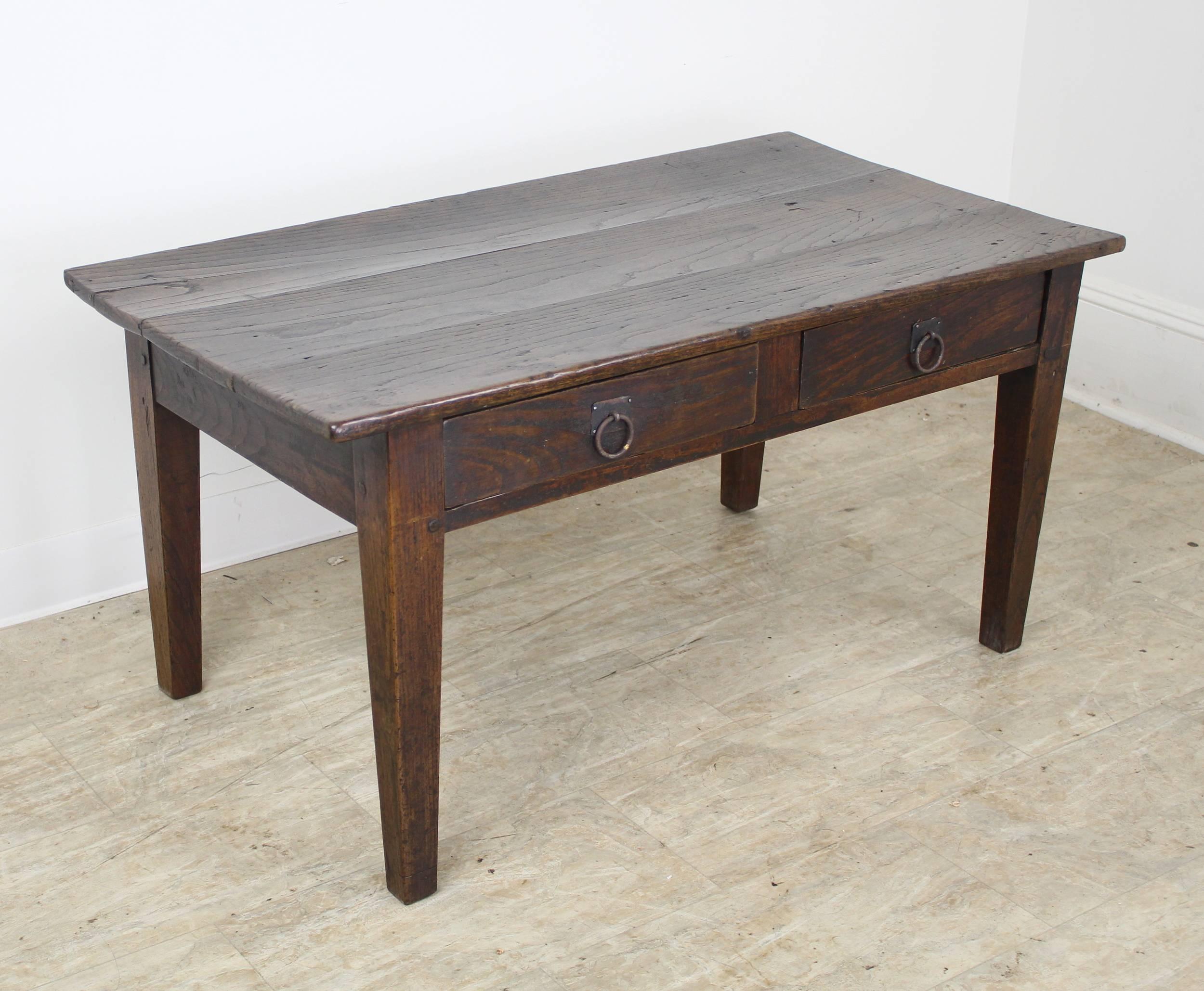 A sturdy and handsome dark chestnut coffee table, with two drawers for storage and visual interest. Wrought iron rings lend a rustic look. The chestnut has great grain and patina. Nice size for most rooms.