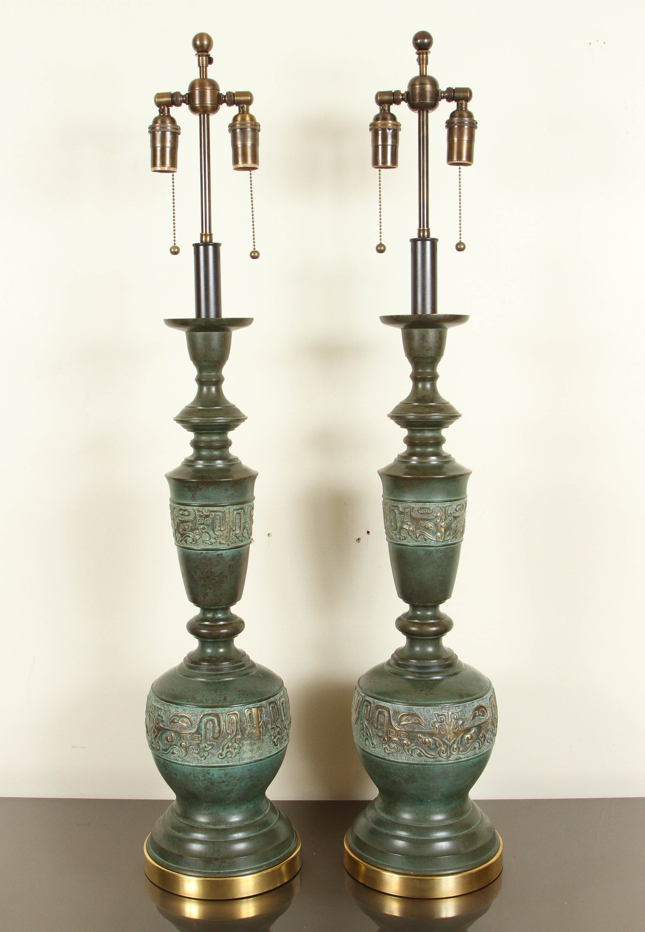 Large pair of metal table lamps with a verdigris bronze finish by Marbro.   
The  large lamp bodies have a band with a design detail highlighted  in gold and they sit up on brass bases.  The lamps have been newly rewired with  bronze finished