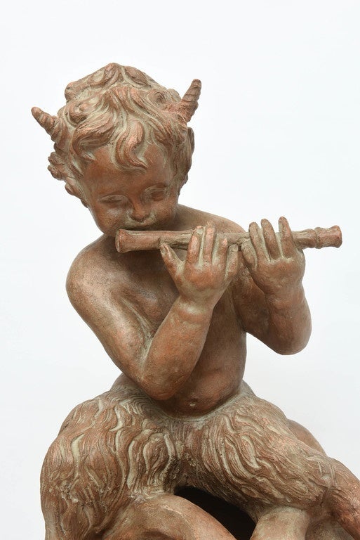 Charming terra cotta Pan with flute seated on sphere.