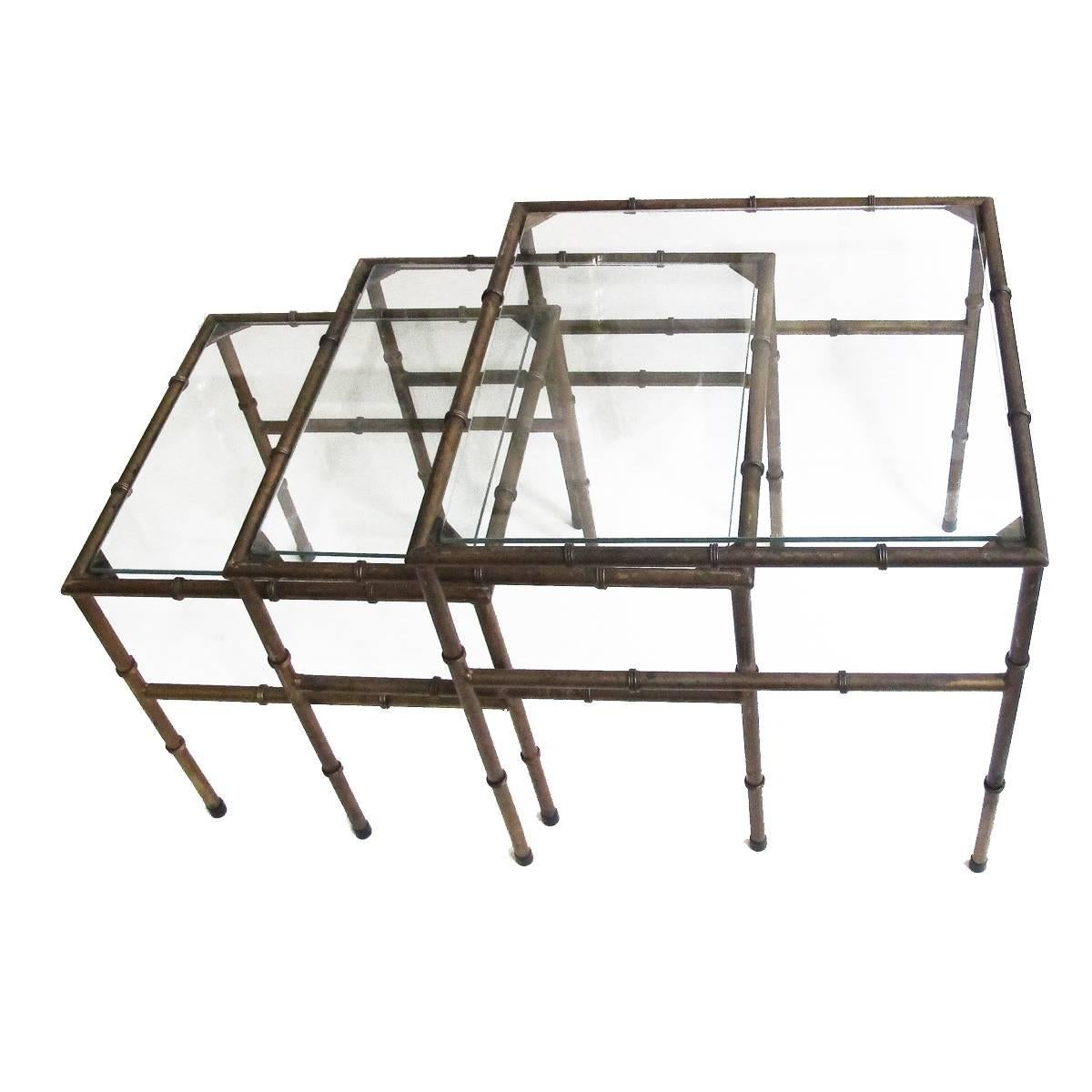 1960s set of three iron faux bamboo nesting tables with glass tops, with pleasantly-worn old gold paint. Dimensions below are for the largest table, the others are: Medium table: 17.5 in cube, small table: 15.5 in cube. Price is for the set of three.