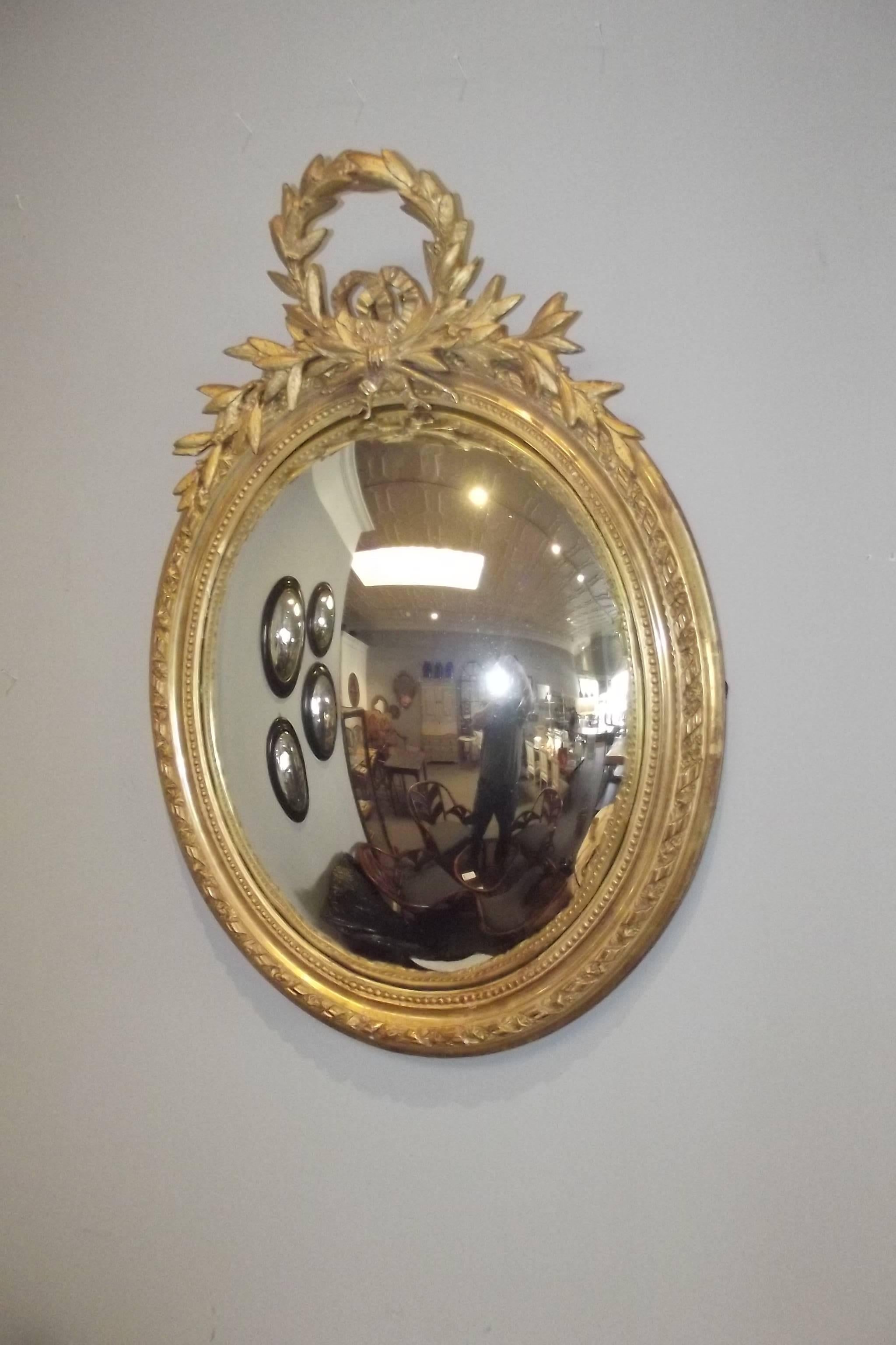 An extremely large scale oval mirror with a gilt frame in the style of Louis XVI and a convex mirror.  It dates from the middle of the 19th century and retains much of its original gilt finish.
