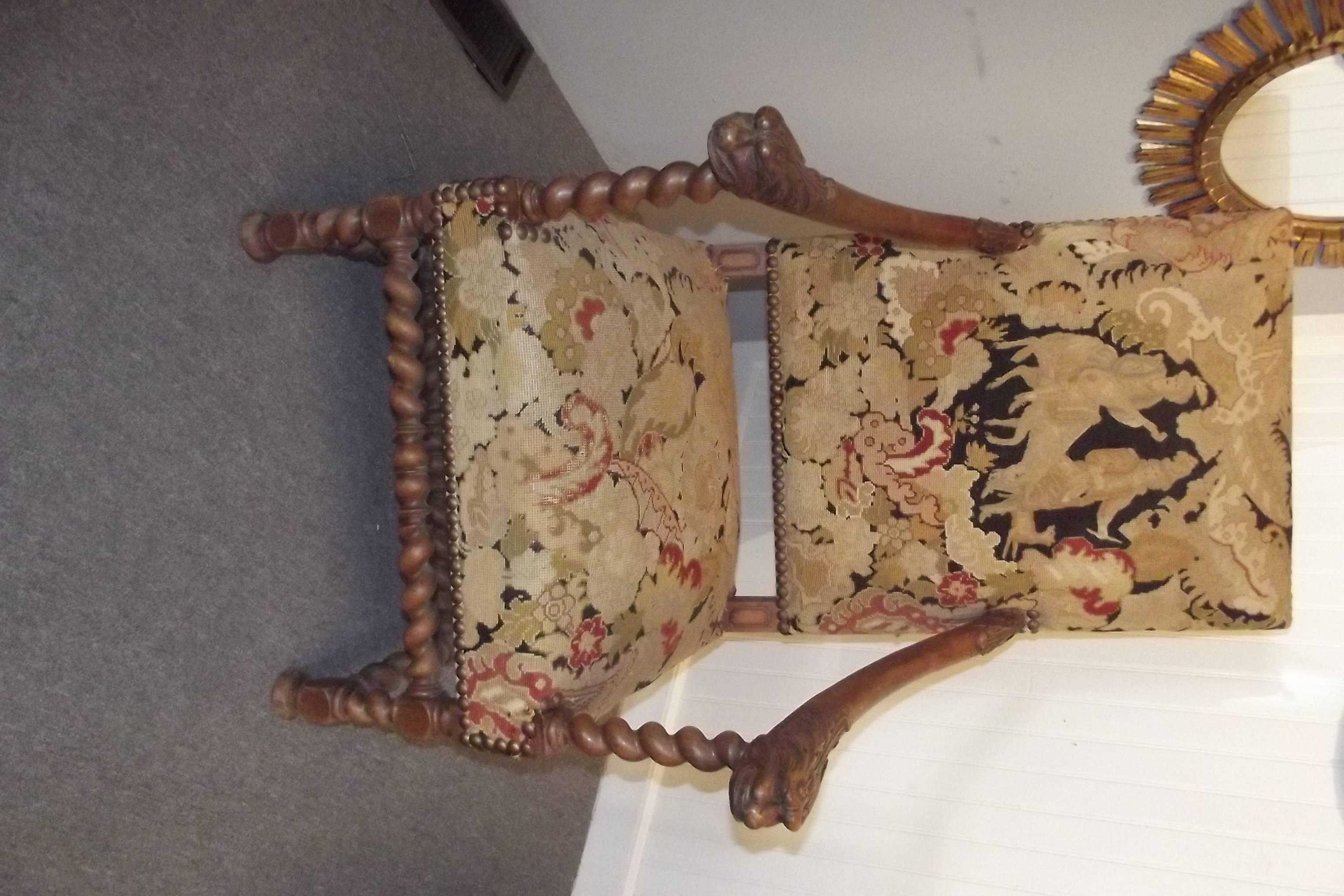 A pair of armchairs in the style of Louis XIII with their original needle point and petite point upholstery.  The frames have extensive overall carving.  The chairs are in good structural condition with expected wear to the original upholstery