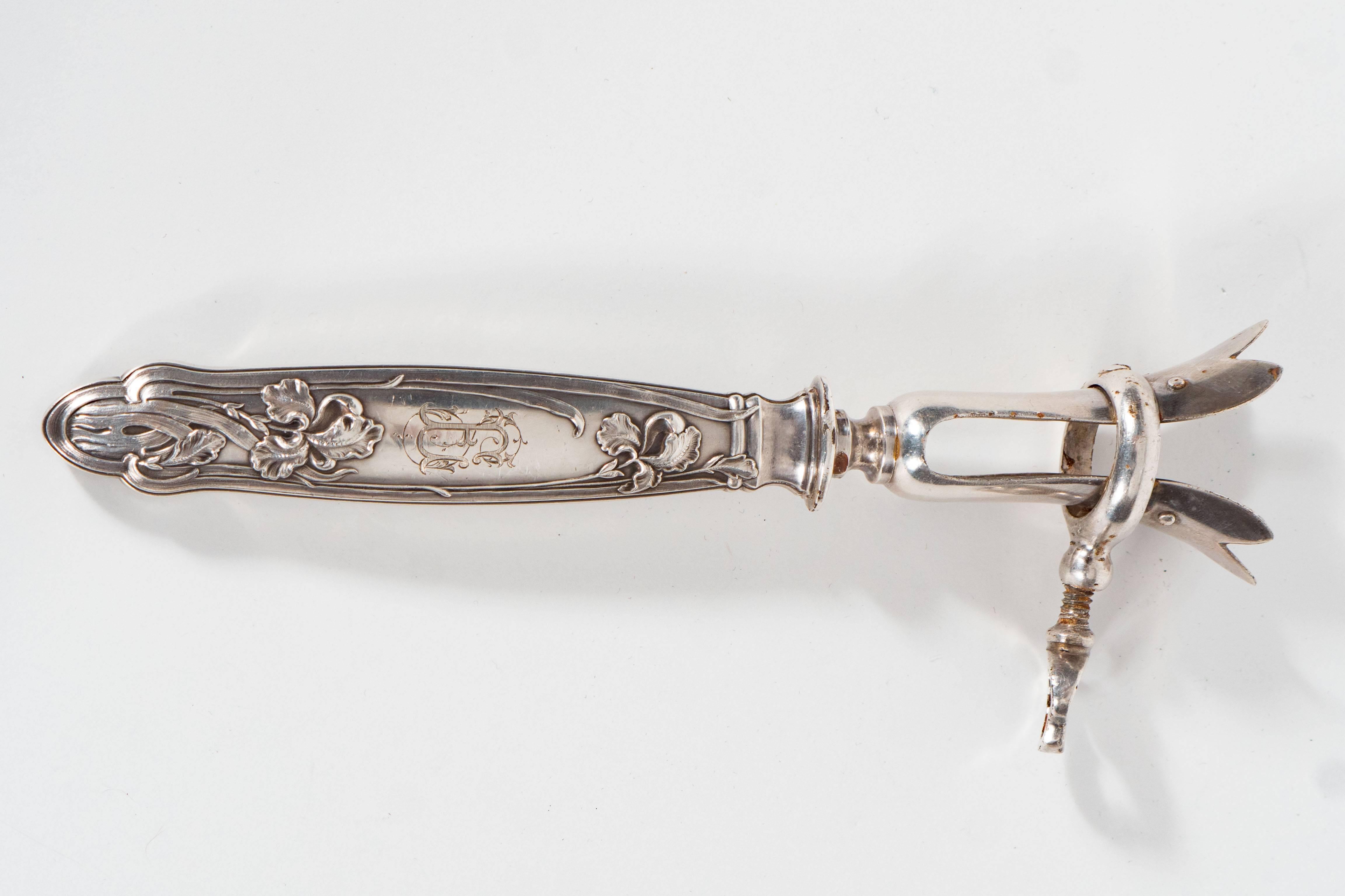 This exquisite Sterling silver joint holder features an elegant iris and foliate motif on the handle, an inscribed Gothic 