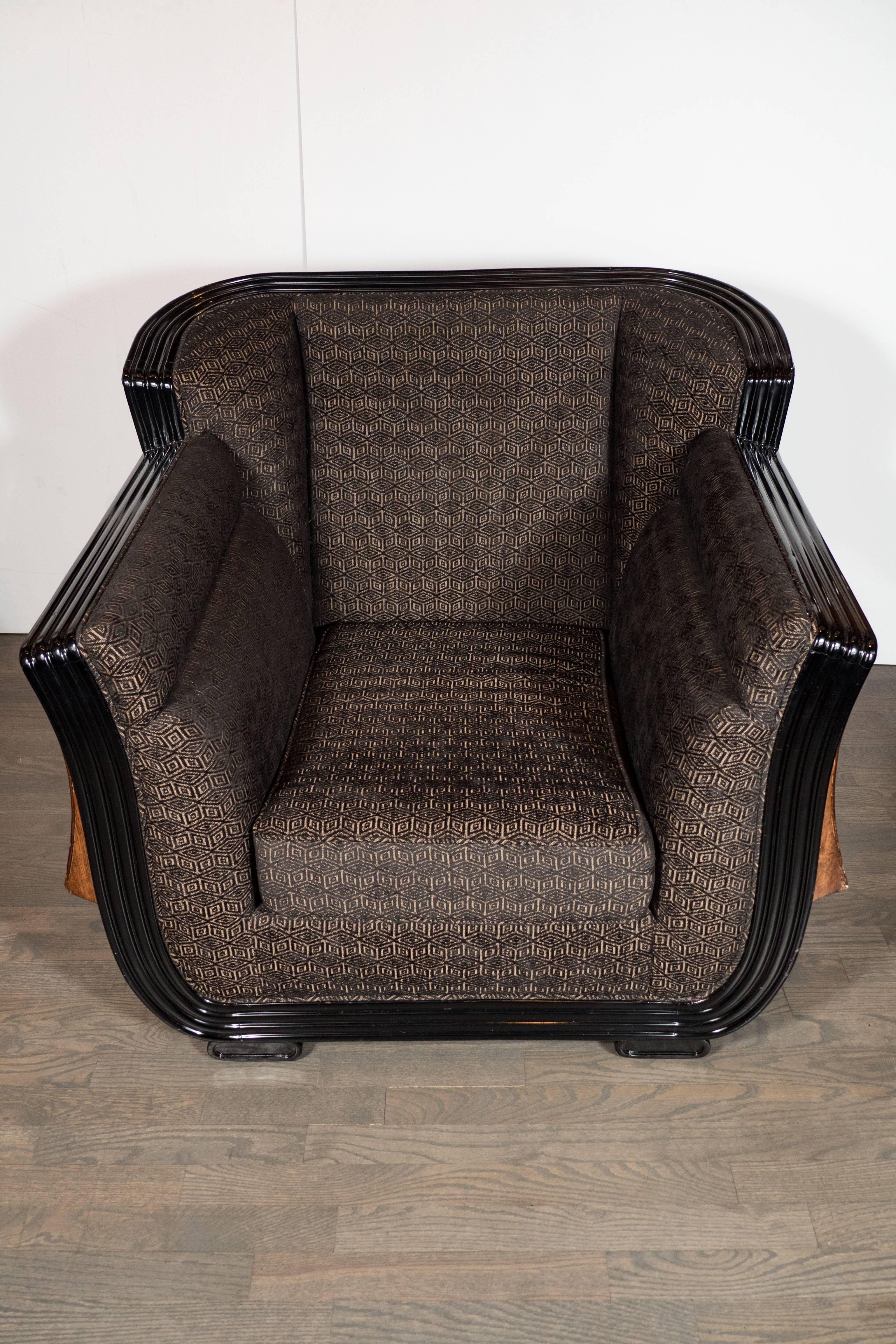 An Art Deco club chair with inlay designs- in exotic elm, burled walnut, mahogany and black lacquer- flanking the sides of the chair. The interior upholstery of the chair is contoured for maximum comfort, it is newly upholstered in a geometric