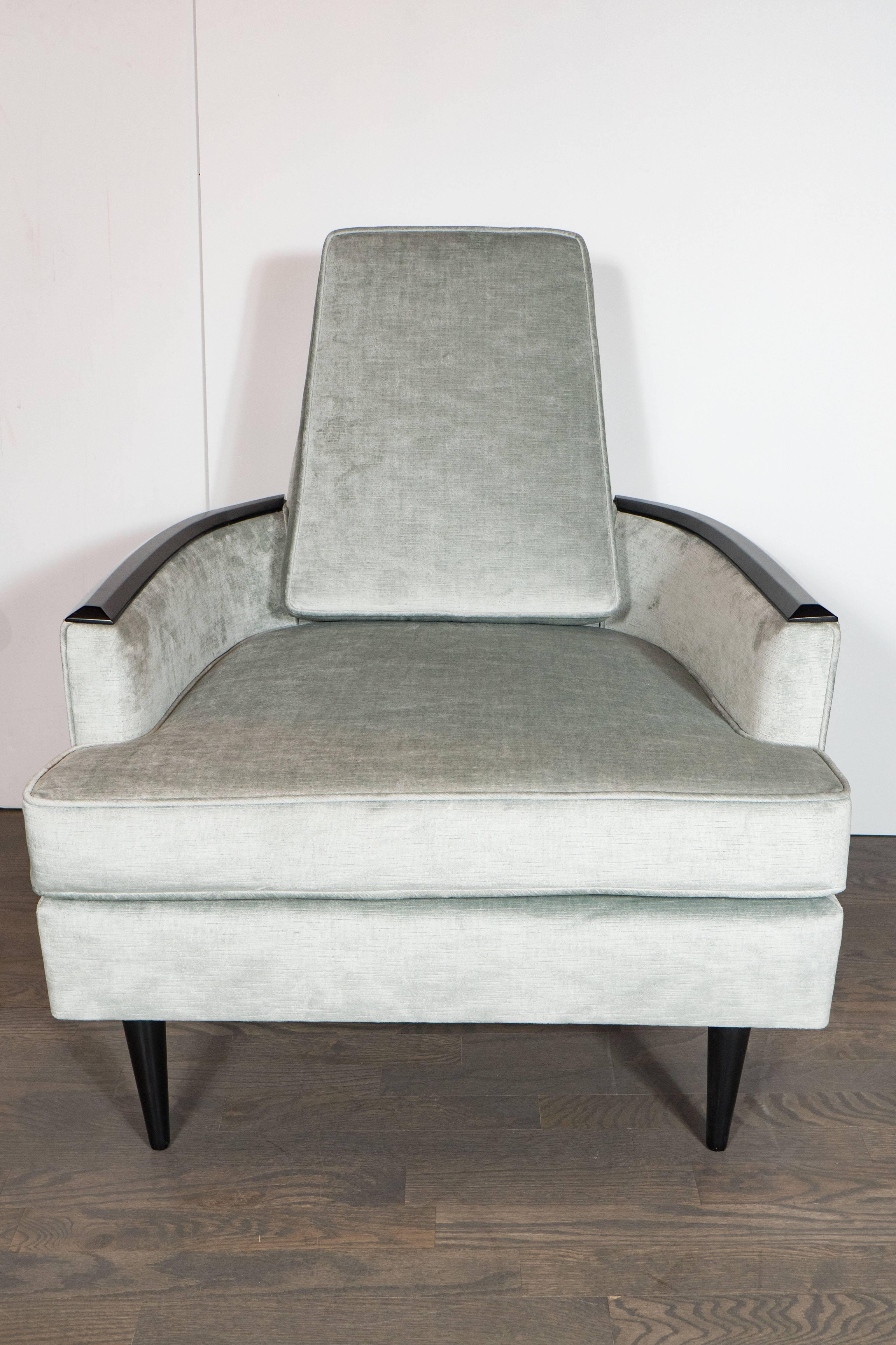 This stunning and sculptural pair of Mid-Century Modernist armchairs were realized in the Untied States circa 1950. They feature conical feet, gently tapered backs, and sinuously curved arms with ebonized walnut detailing throughout. With their