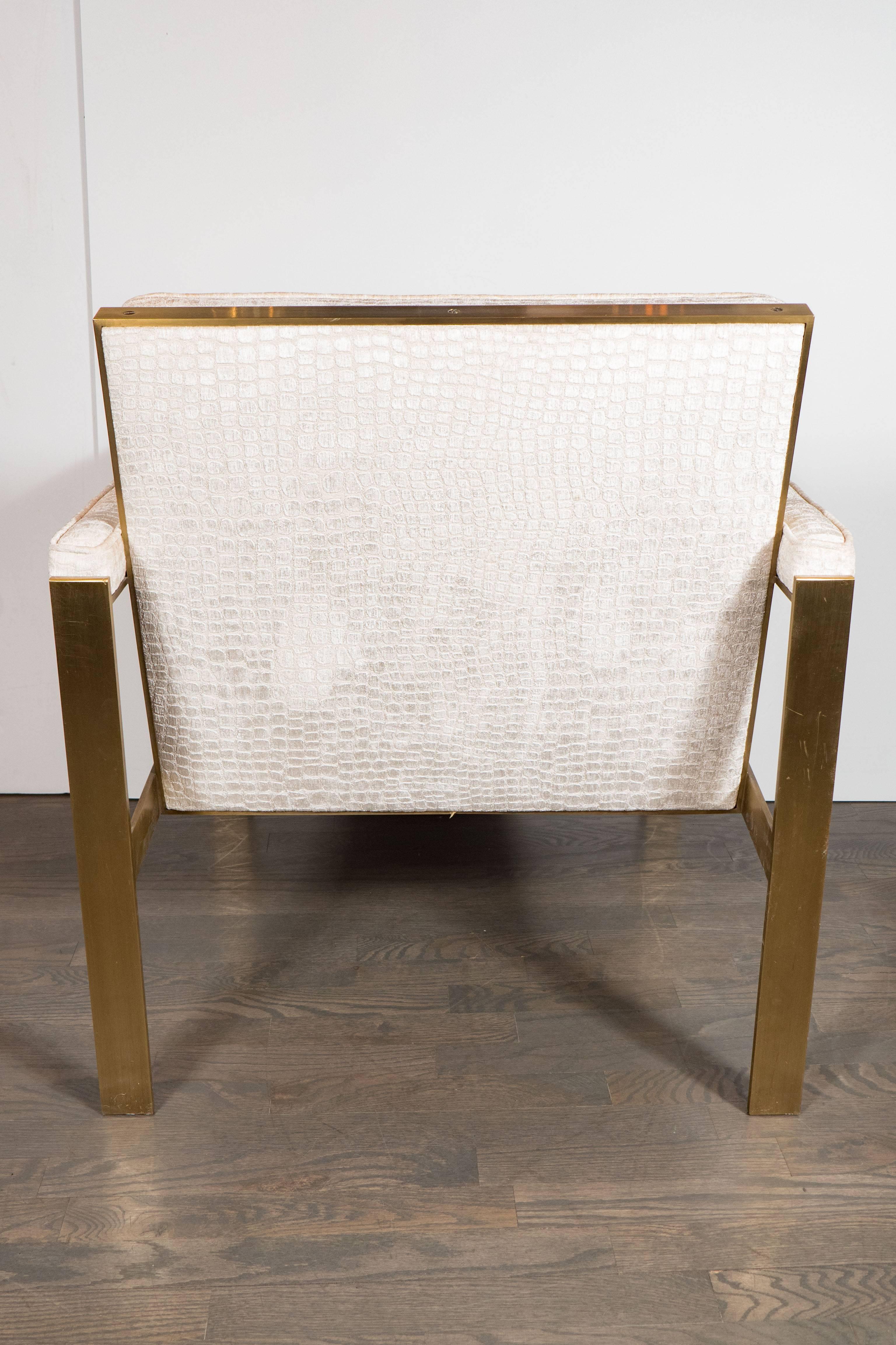 A pair of Mid-Century Modernist brass armchairs by Milo Baughman. The entire frames are a brushed brass. The cushions and full-arm supports have been newly upholstered in a luxe smoked oyster gaufrage crocodile-textured velvet. The design of the