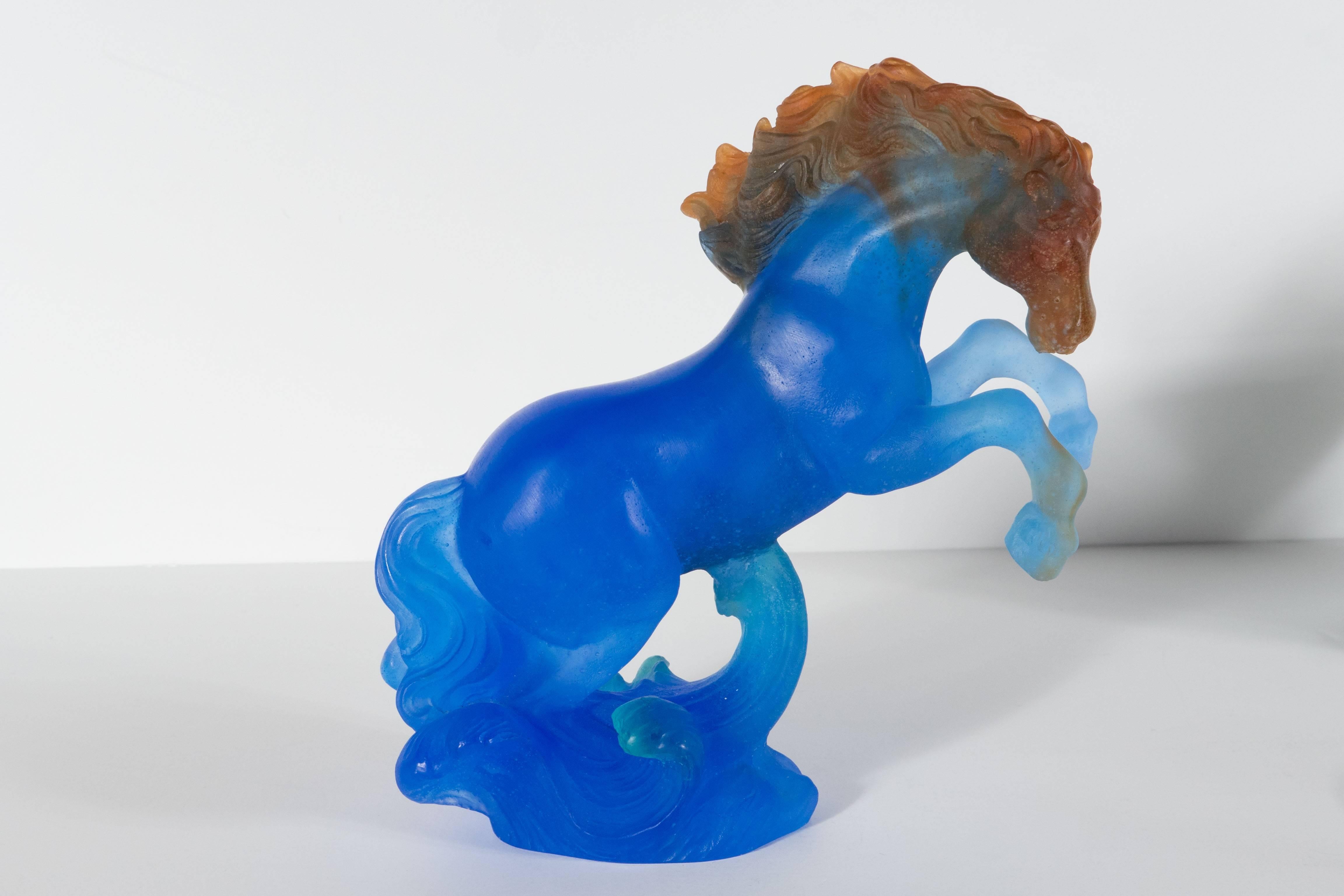 A Daum Pate de Verre art glass stallion in royal blue with crimson and green hued detailing. This piece depicts a stallion in movement, graciously battling a series of outgoing waves. A wonderful example of pate de verre, a near-extinct method of