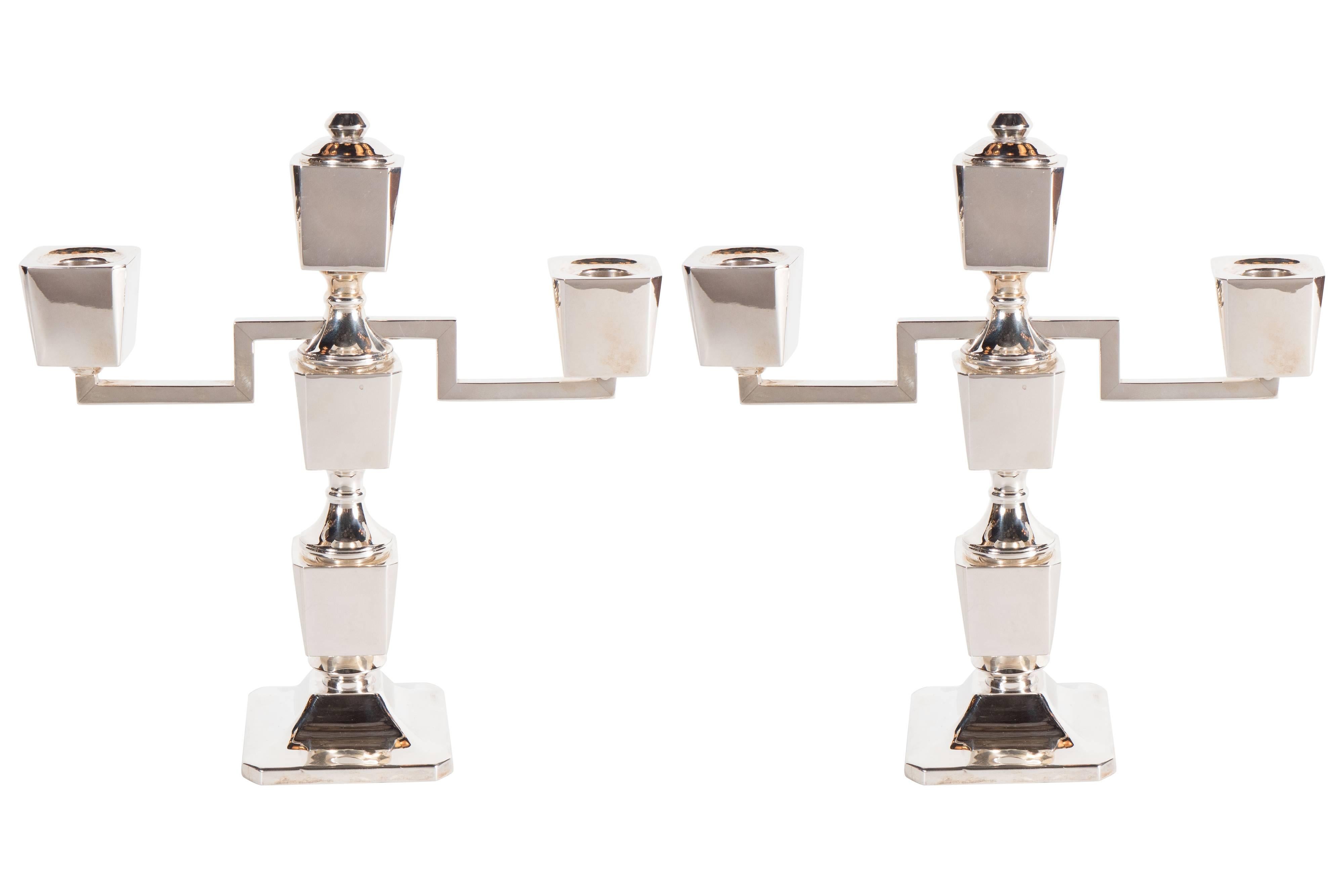 An Art Deco pair of modernist customizable/adjustable sterling silver candlesticks. Each candlestick can be modified to adjust its height in five different ways to either support one, two or three candles. A decorative and functional cap piece can