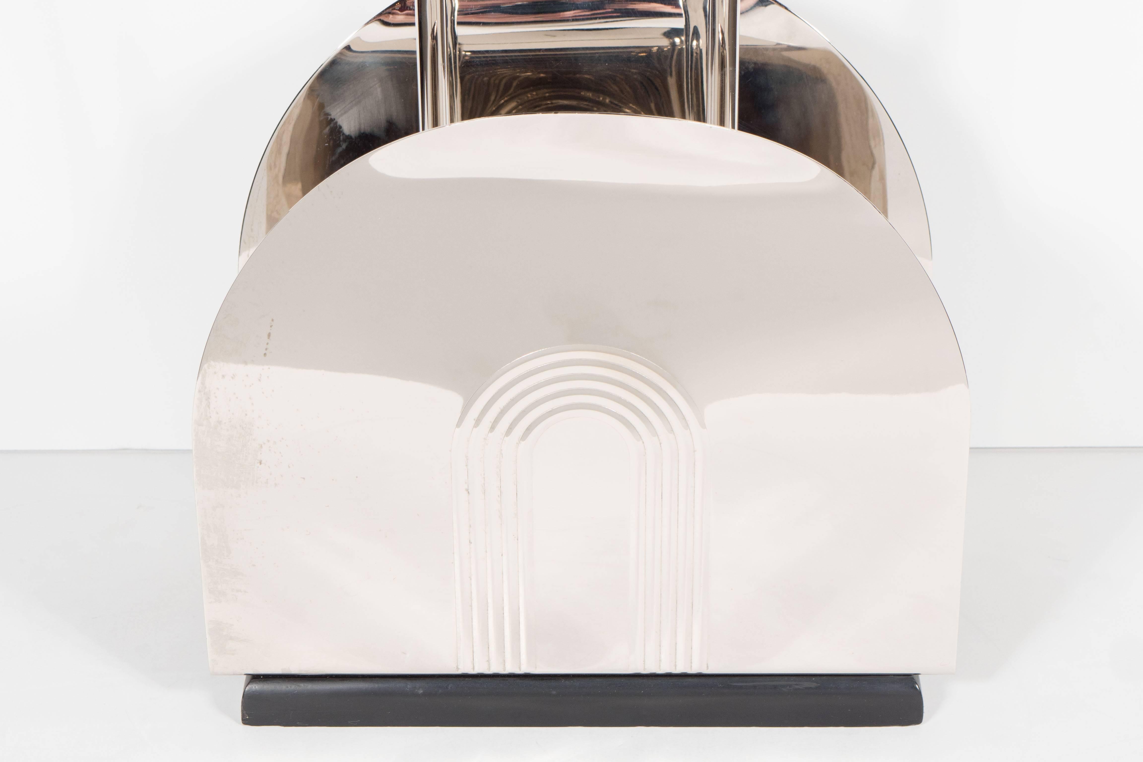 A streamlined Art Deco magazine stand in polished nickel and black enamel base. This rare magazine stand features a streamline arched design with relief stepped skyscraper style arches on both sides all in polished nickel resting on a black enamel