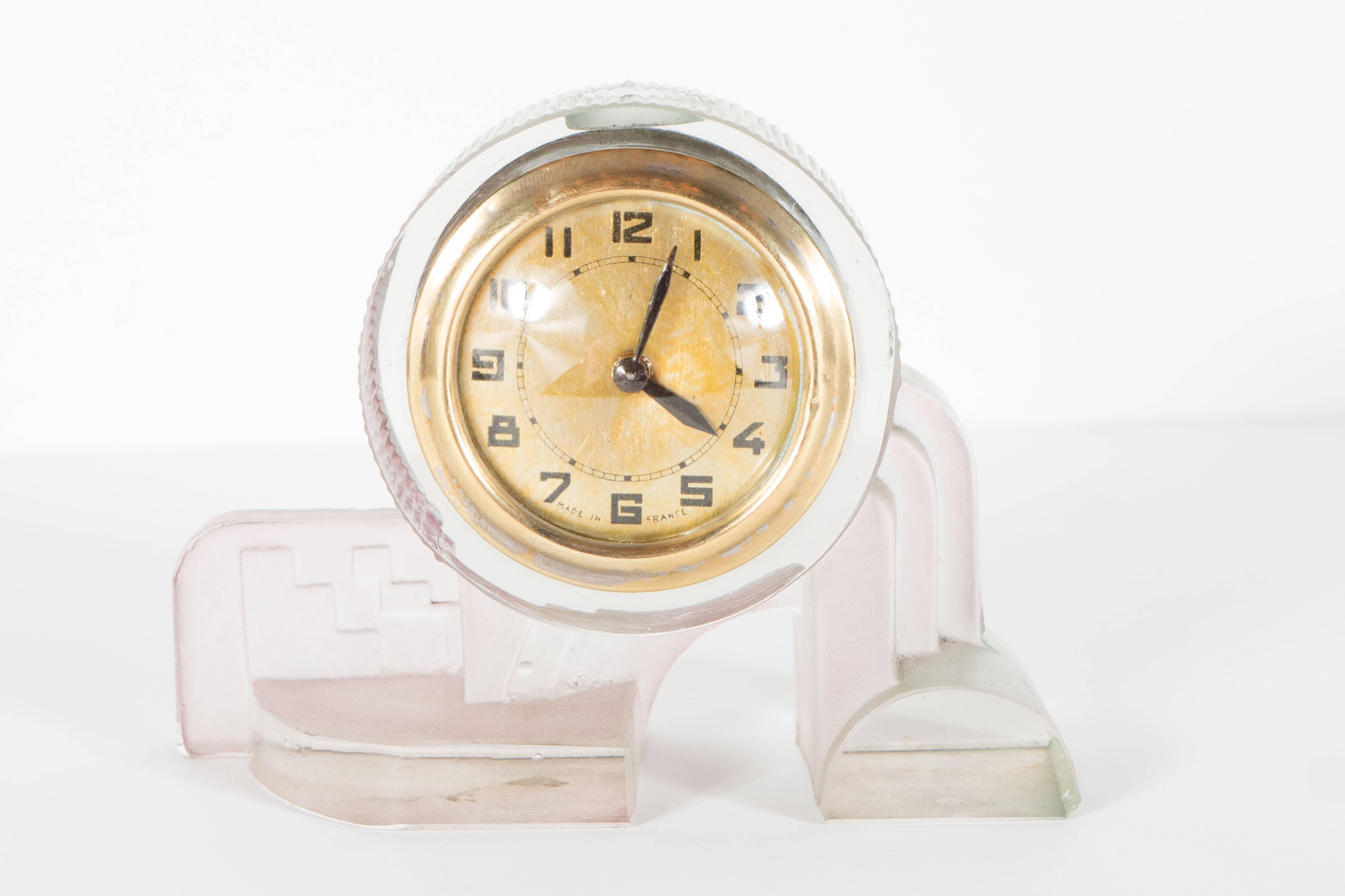 A French Art Deco table or desk clock in pale and rose celadon pressed glass. A geometric cubist base supports a ribbed clock. The entire piece is comprised of slightly hued pressed glass. Wind-up mechanism intact and functional. A beautiful piece