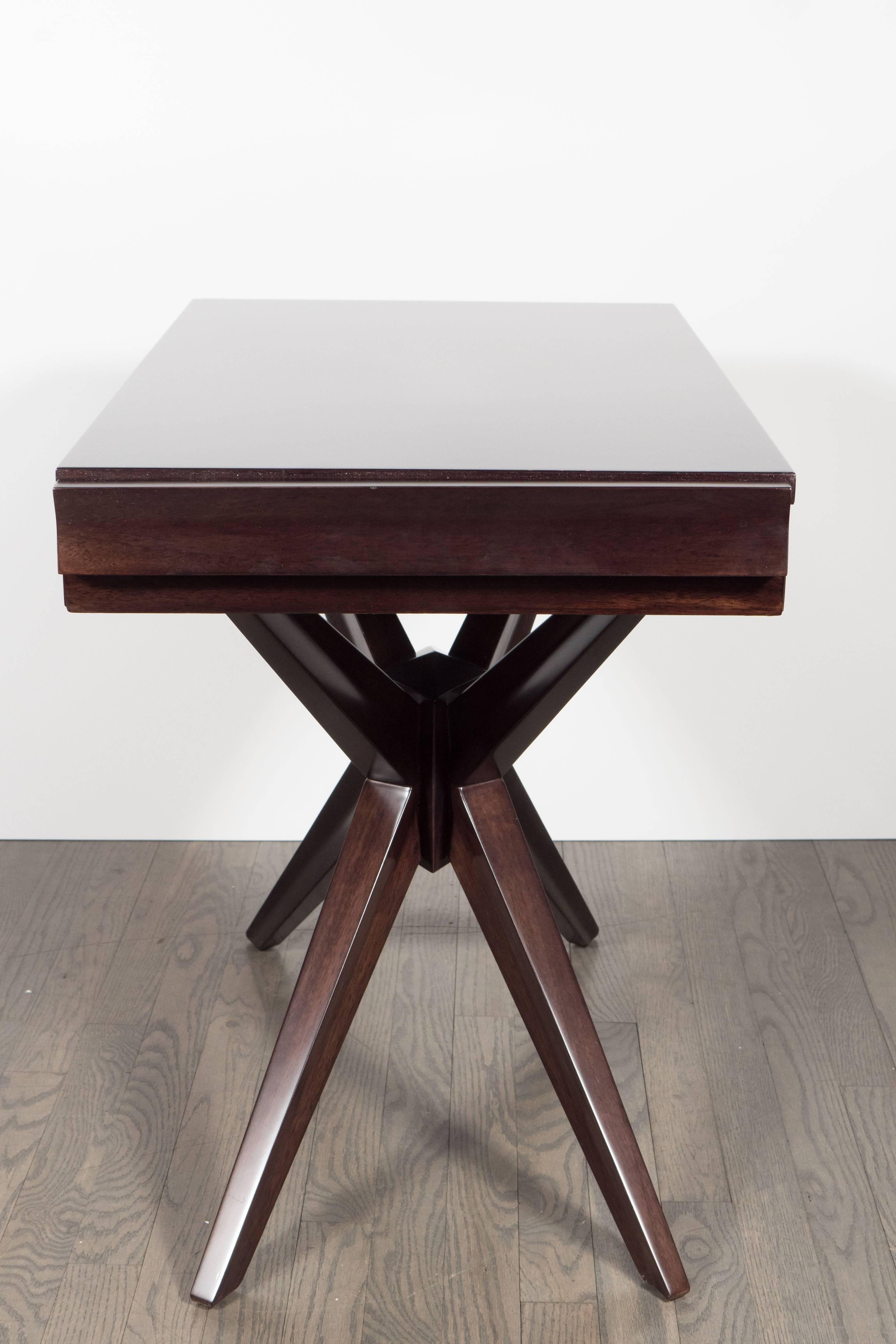 This graphic Mid-Century Modern sculptural end table was realized in the United States, circa 1950. It features splayed legs forming an X-base all crafted in ebonized walnut. Four angled, slightly tapered splayed legs stem from a central support.